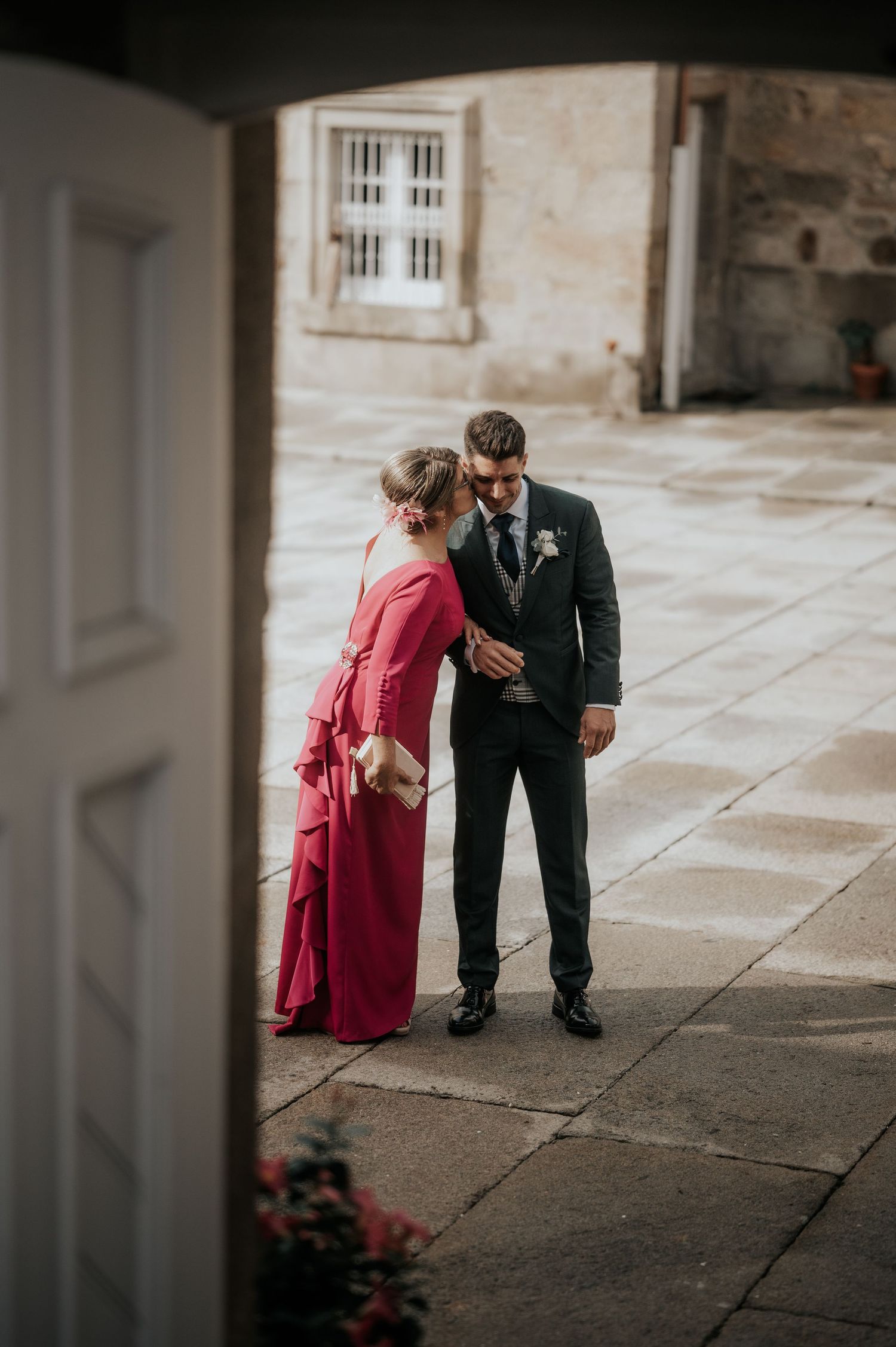 A couple shares a tender moment together in a stone corridor with dramatic lighting and shadows.
