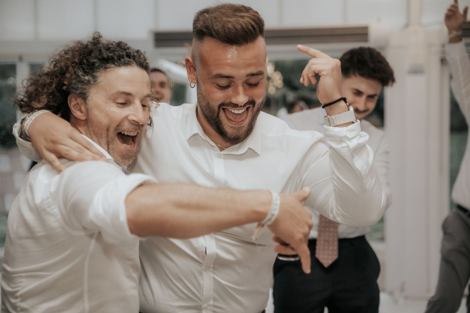 Wedding guests celebrate and dance together at a lively reception party in white attire.