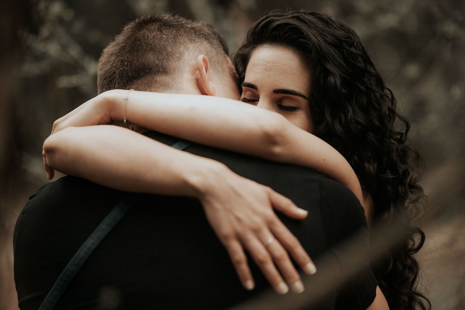 A couple in a romantic embrace share an intimate moment outdoors in warm, moody lighting.