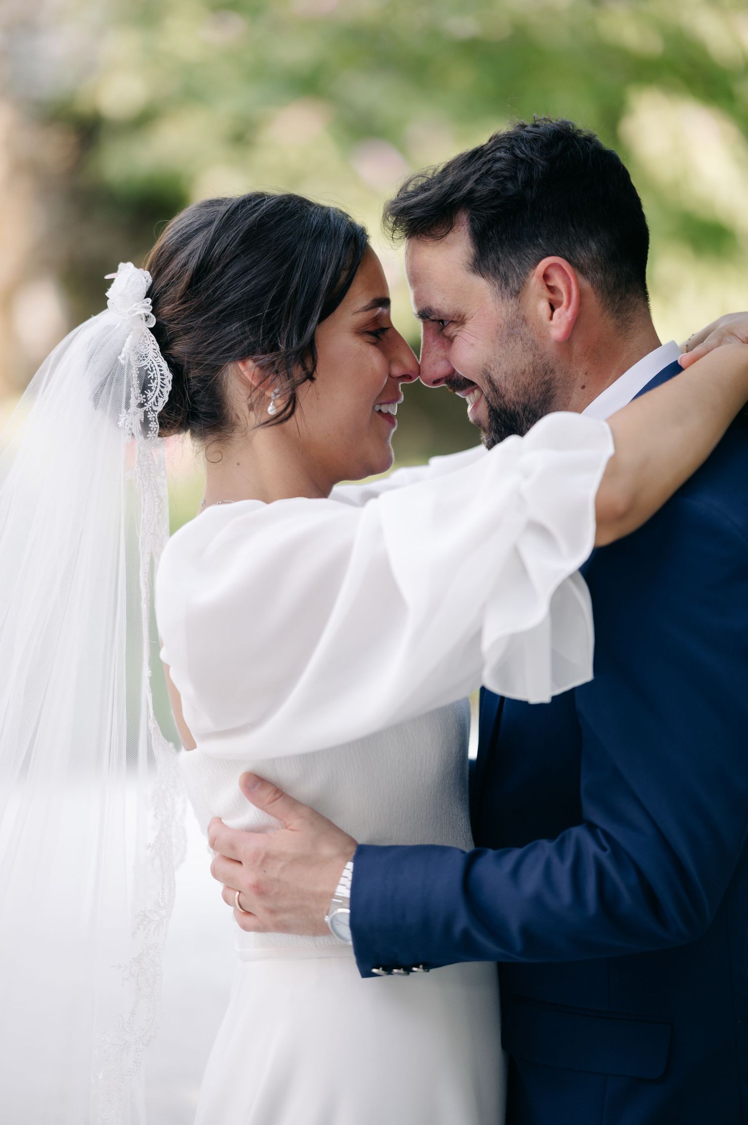A romantic wedding moment captured as newlyweds share an intimate embrace outdoors in natural lighting.