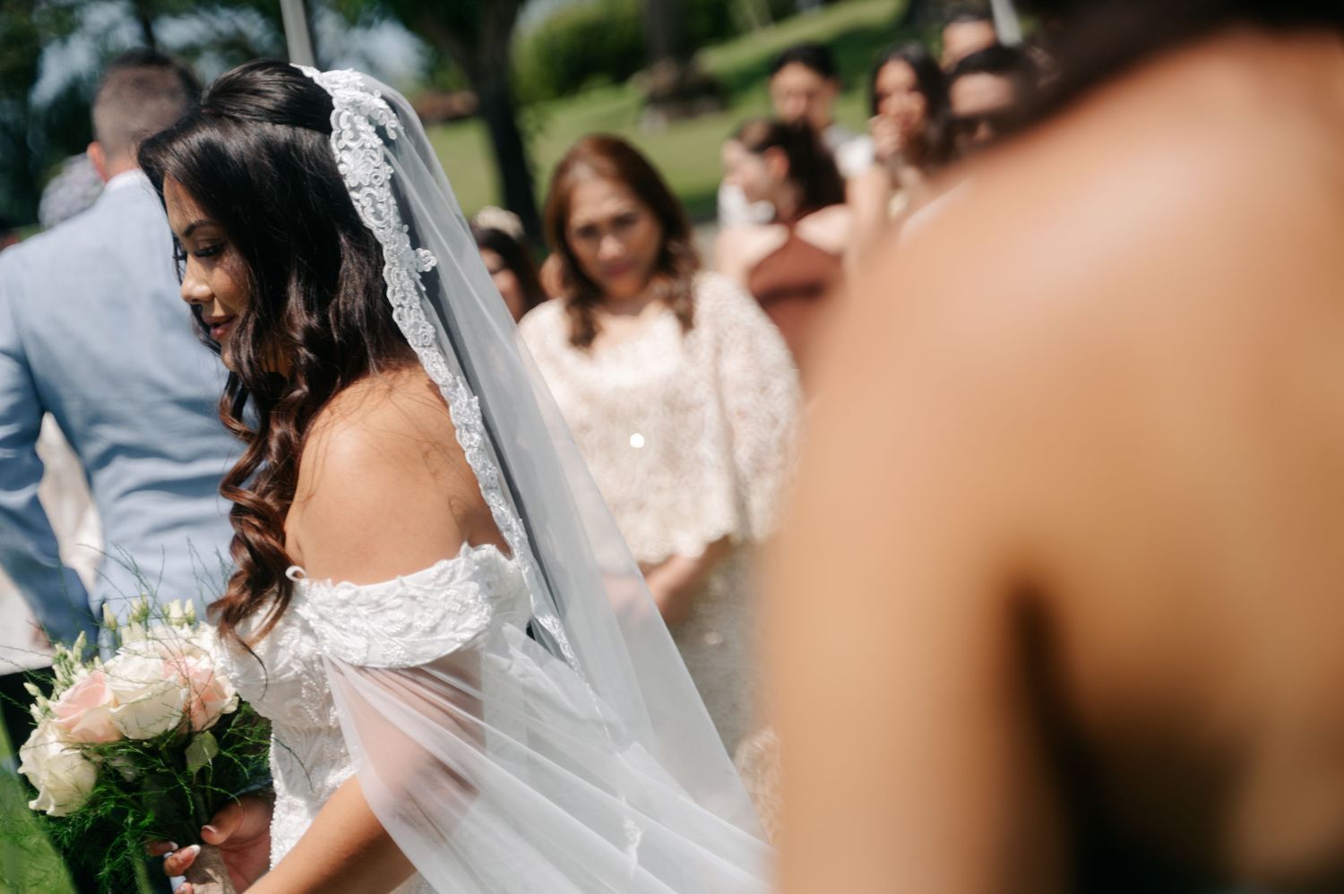 Wedding guests celebrate and dance together during an outdoor reception under natural lighting.