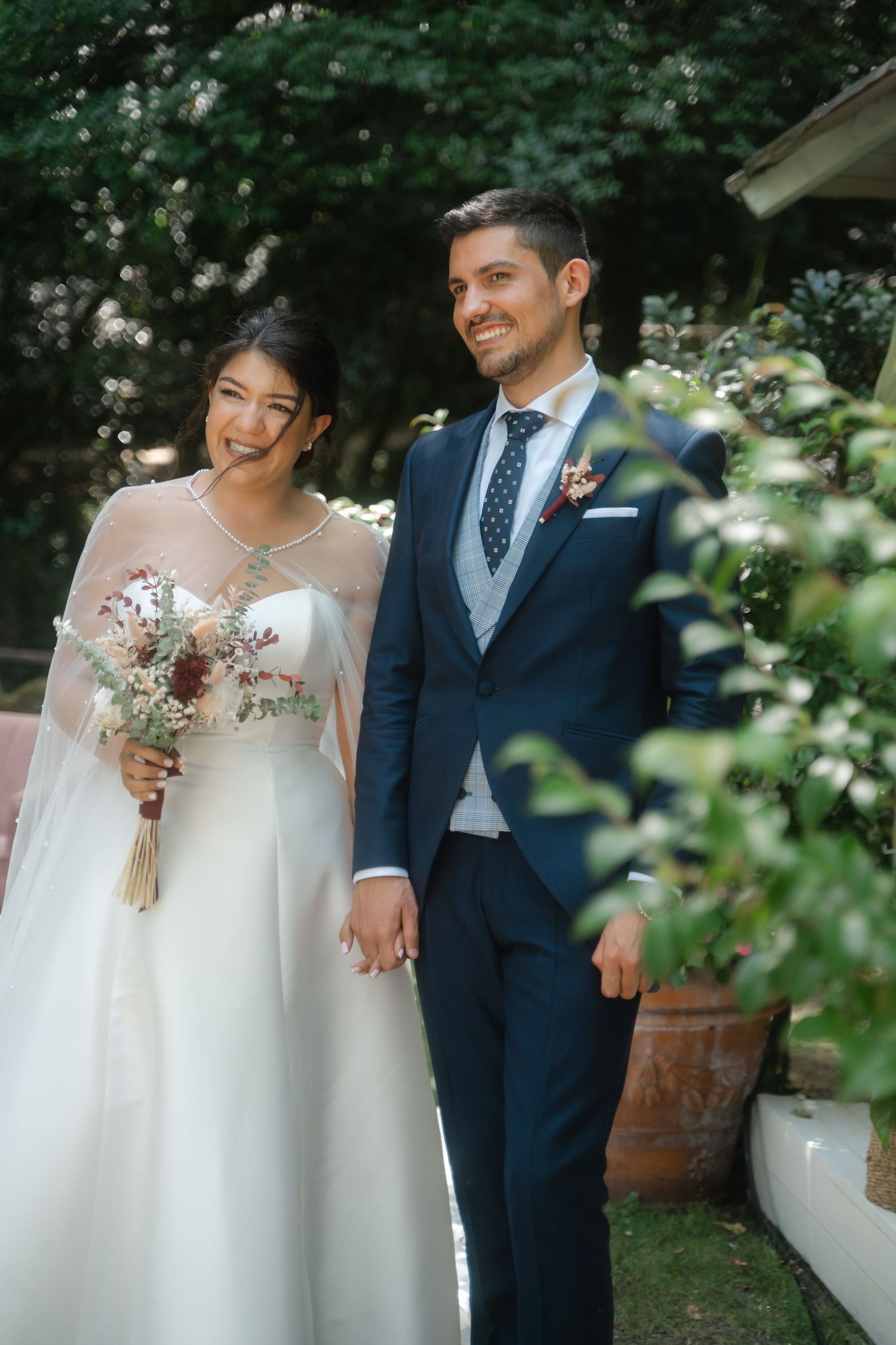 A wedding couple shares a joyful moment together in an outdoor garden setting.