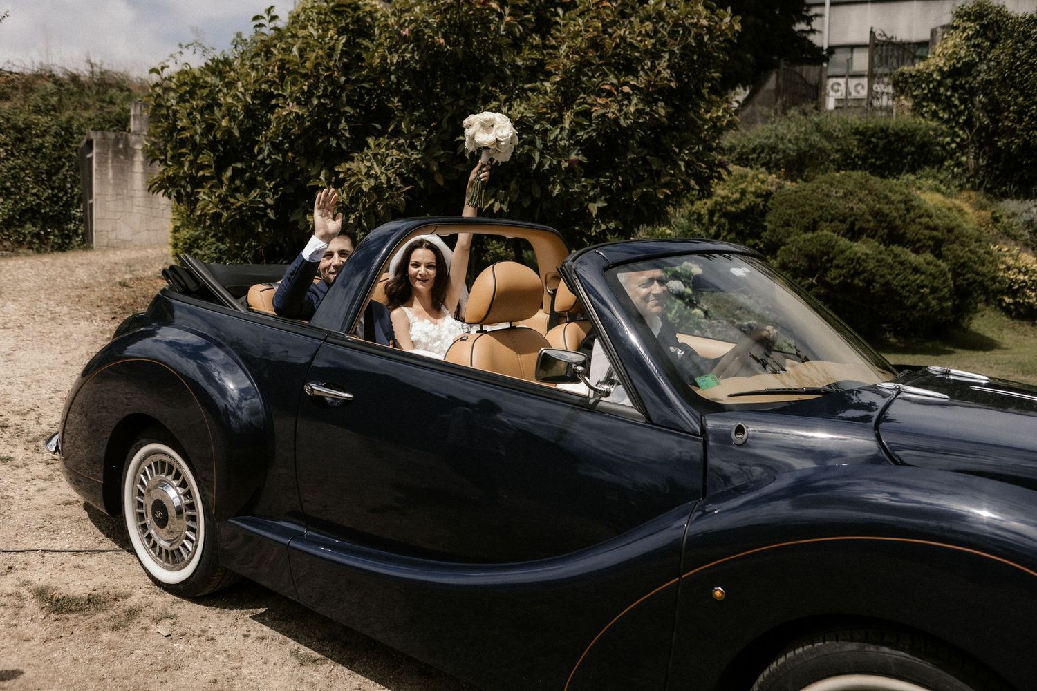 A classic navy blue convertible car decorated with flowers and ribbons for a wedding celebration.
