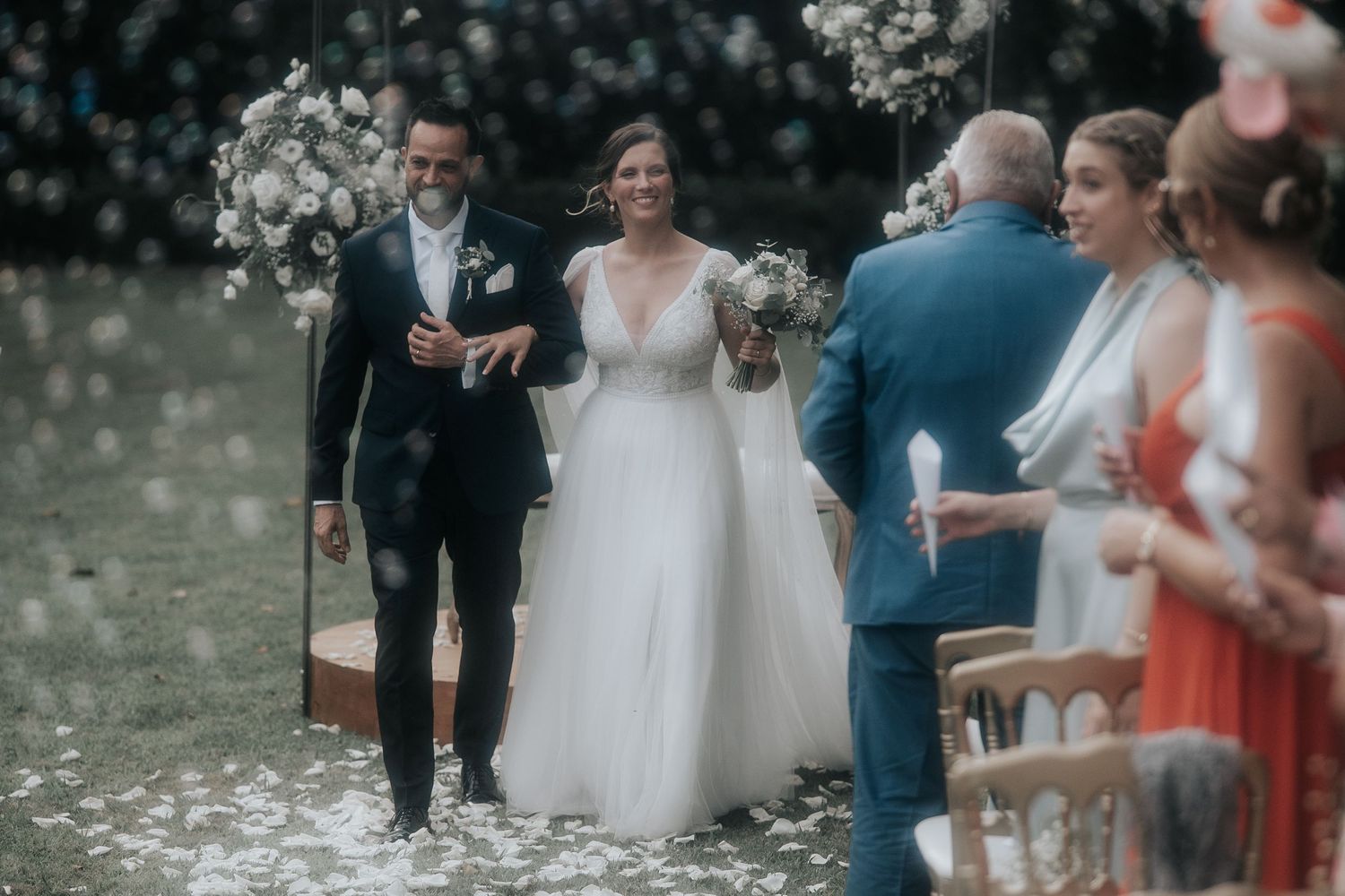 Wedding guests celebrate during outdoor ceremony with coral and white color scheme.
