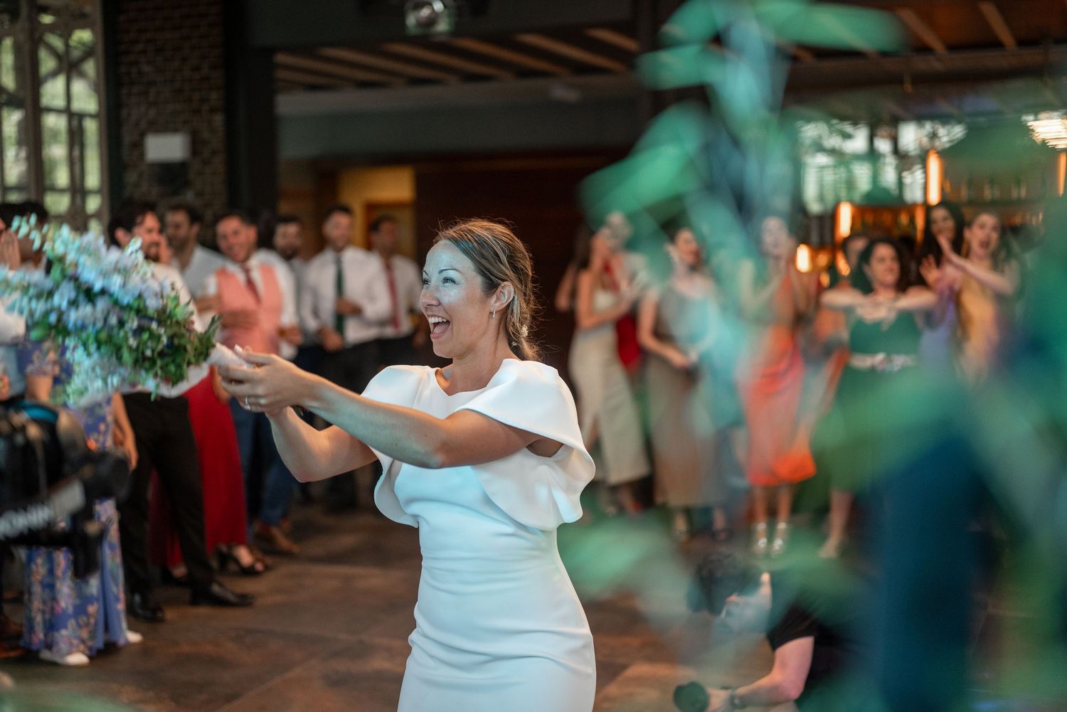 Wedding guests dance and celebrate on a lively dance floor with turquoise lighting effects.