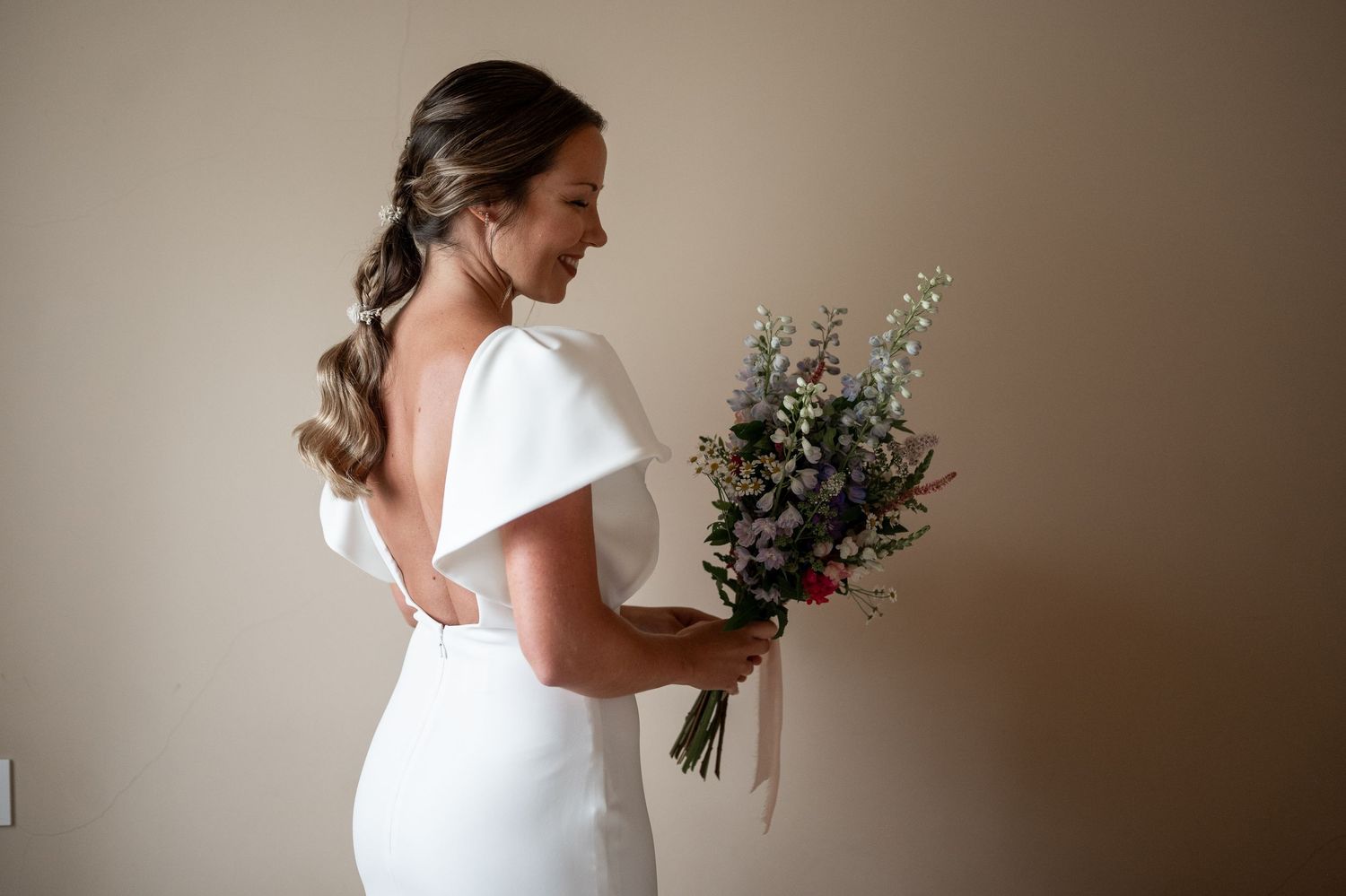 Side profile view of person in white dress holding delicate floral bouquet.