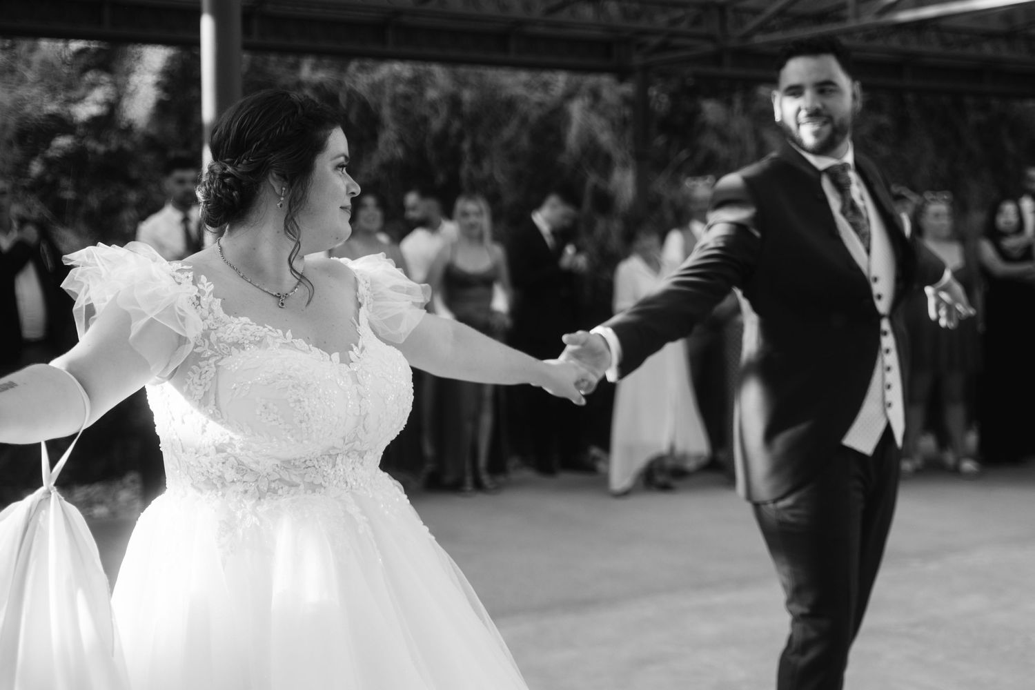 A bride and groom share their first dance together at their wedding reception as guests watch from the sides.