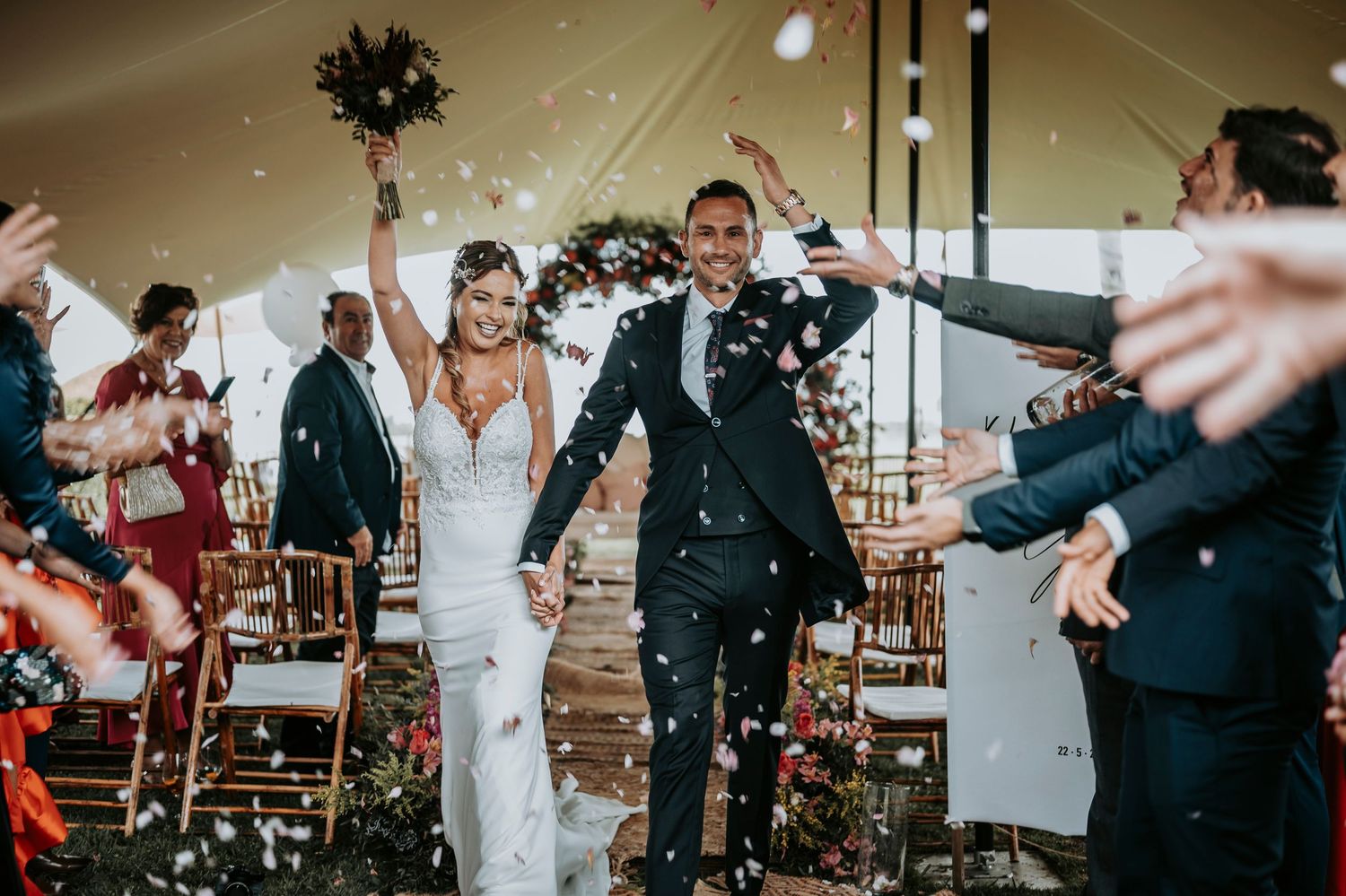 Wedding guests celebrate with confetti and sparklers during an indoor reception at a rustic venue.