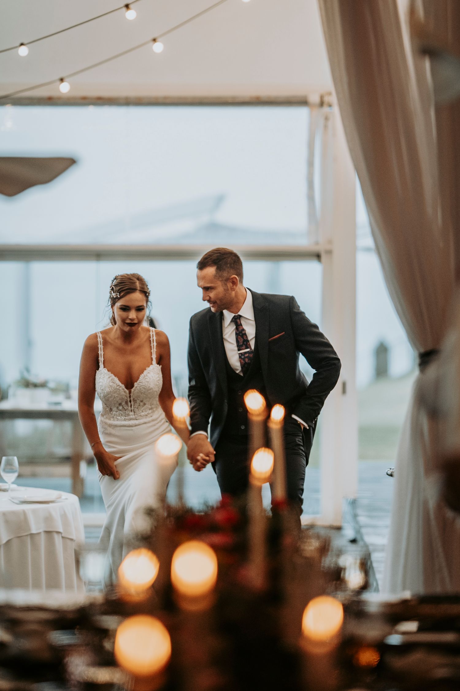 Couple shares an intimate moment at their wedding reception with warm lighting and draped fabric decor.
