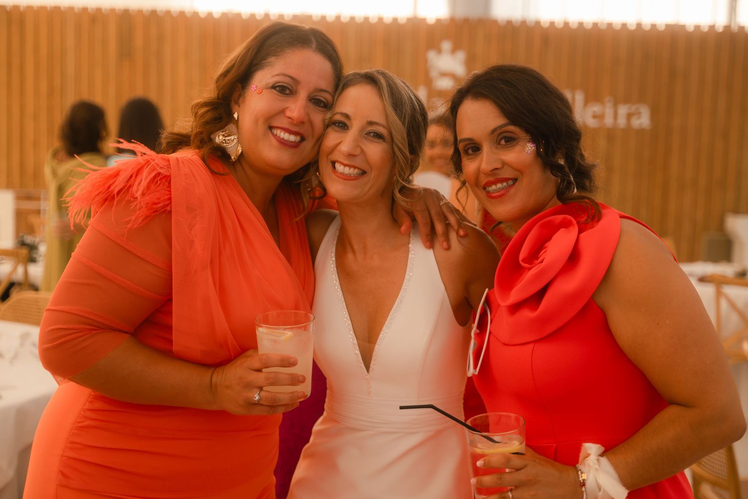 A group of people wearing bright coral and white outfits smile and laugh together at a social gathering.