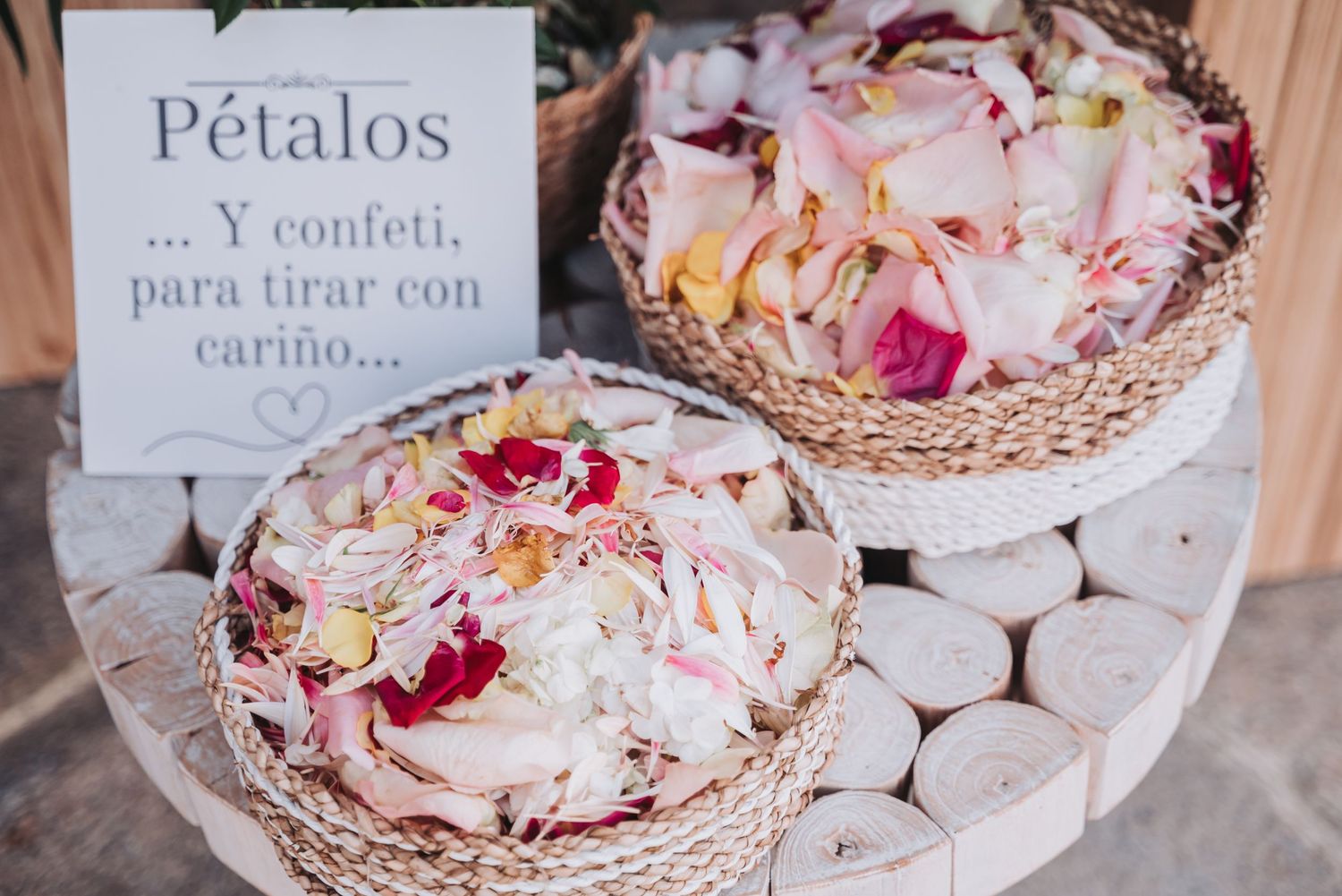 Delicate pink and white flower petals arranged in decorative baskets with Spanish text sign on display.
