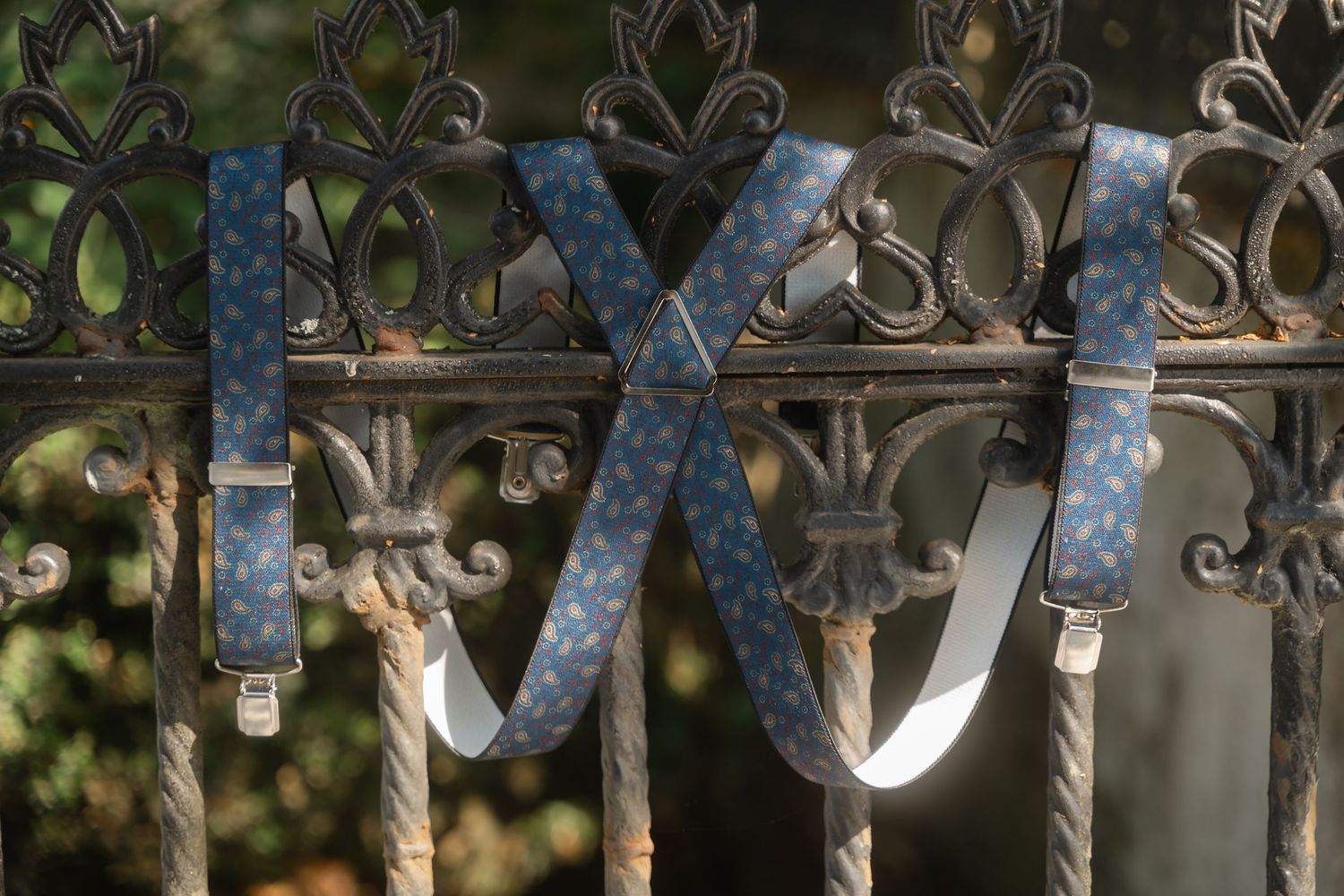 Ornate wrought iron fence details with blue ribbon decorations against a blurred natural background.