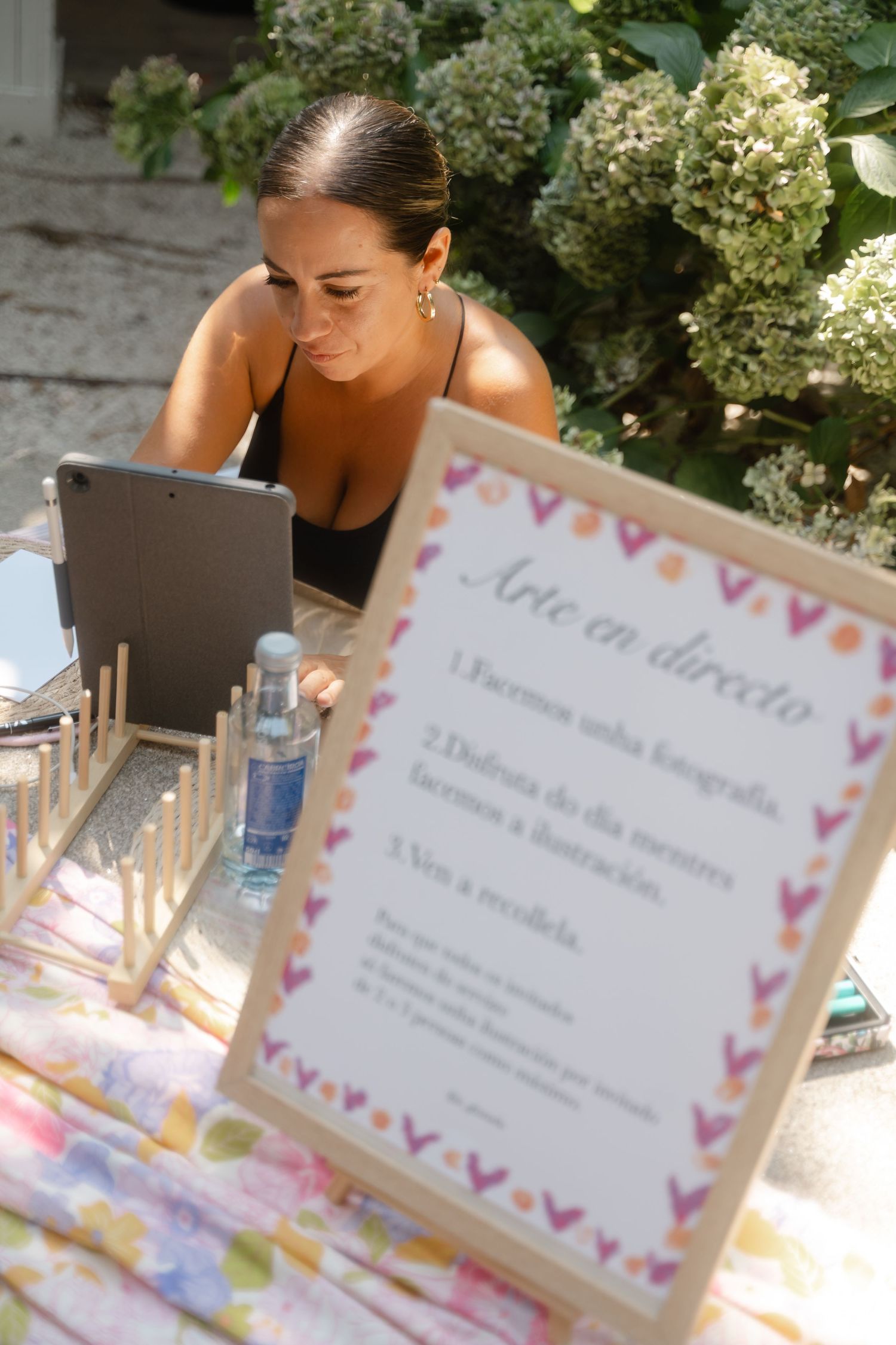 Cards with pink heart borders are displayed at an outdoor event with hydrangea flowers in the background.
