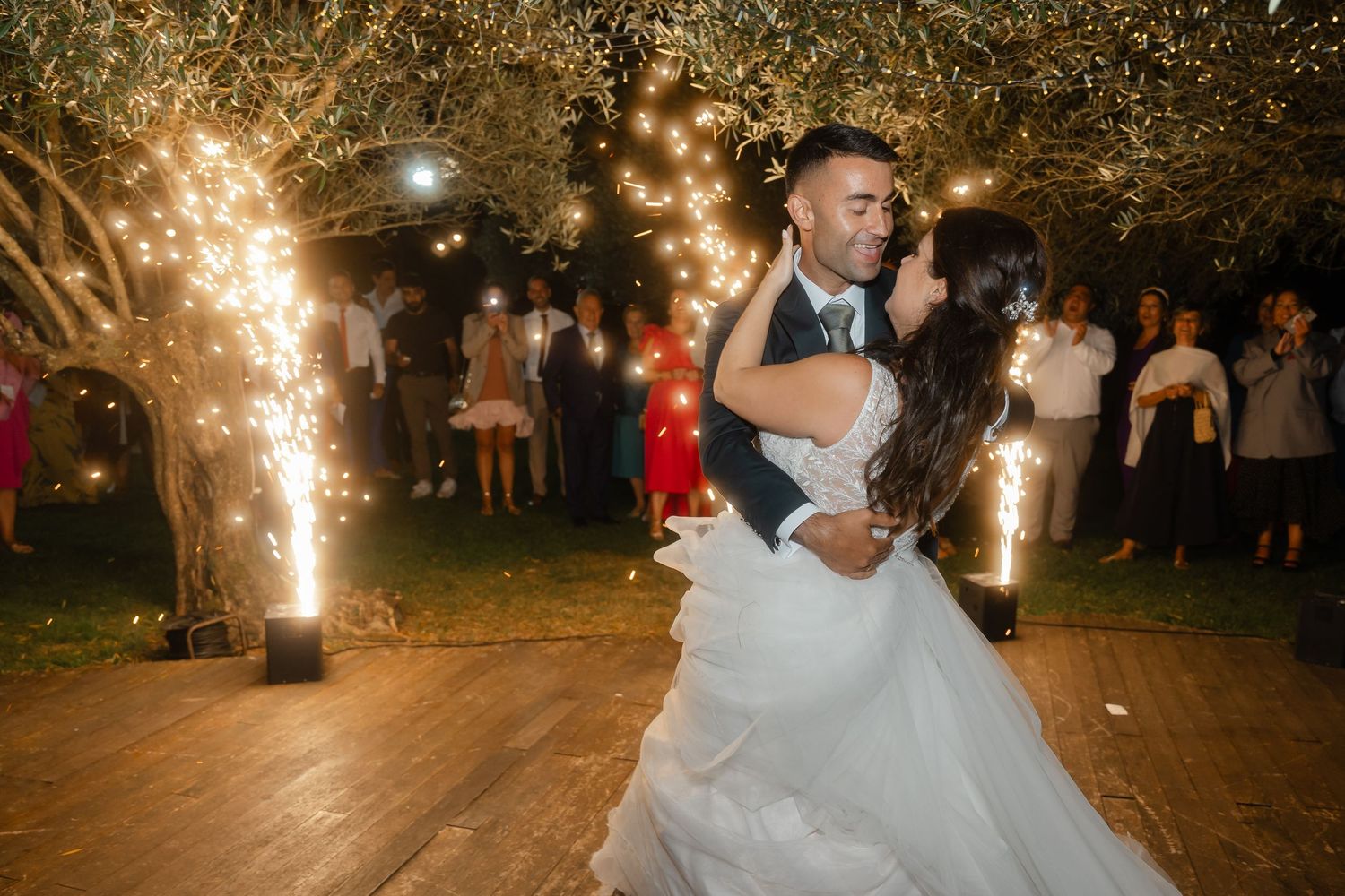 Wedding couple dancing at an outdoor reception with sparklers illuminating the evening celebration.