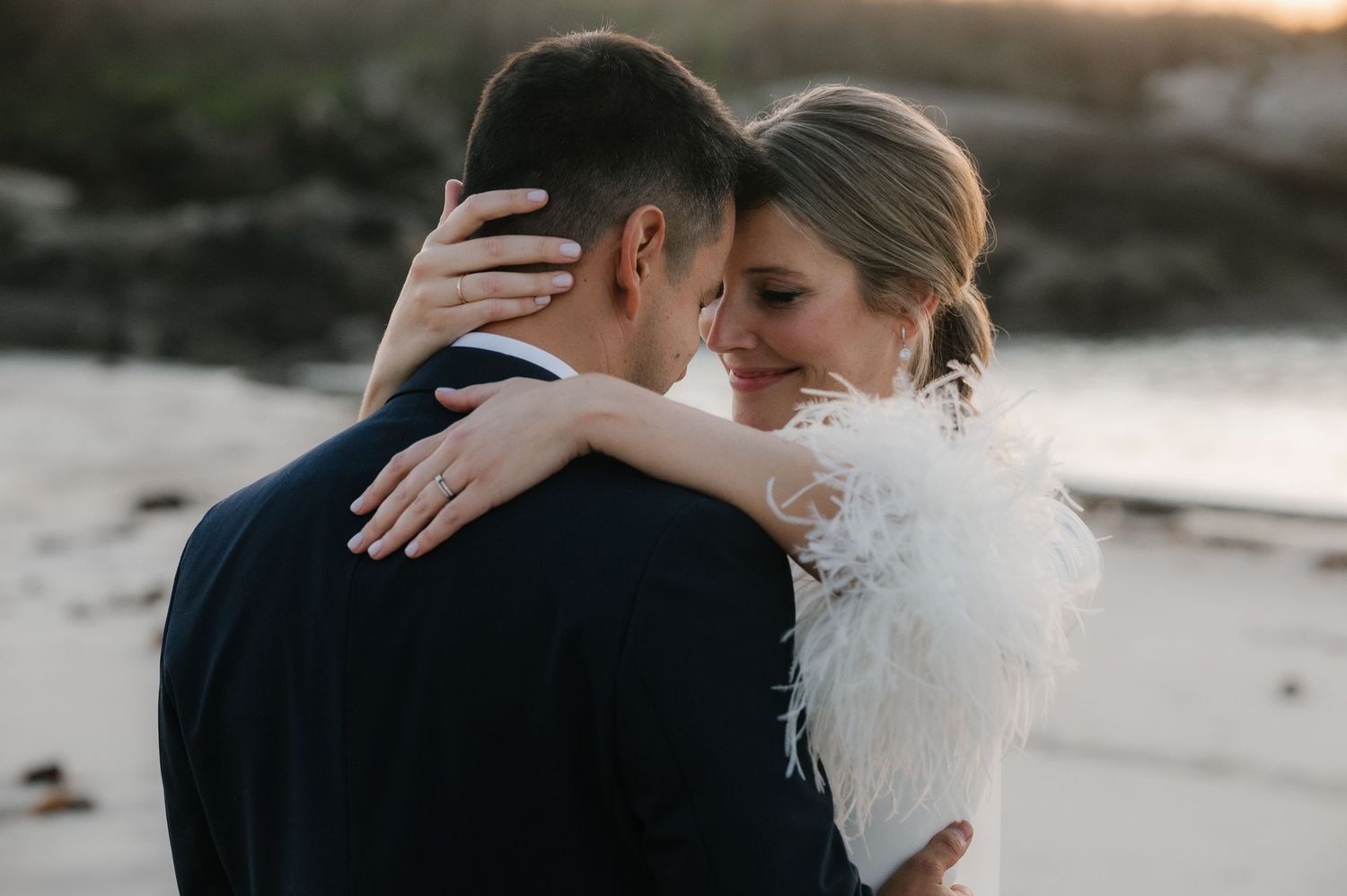 Intimate sunset wedding portraits captured on a beach with soft natural lighting.