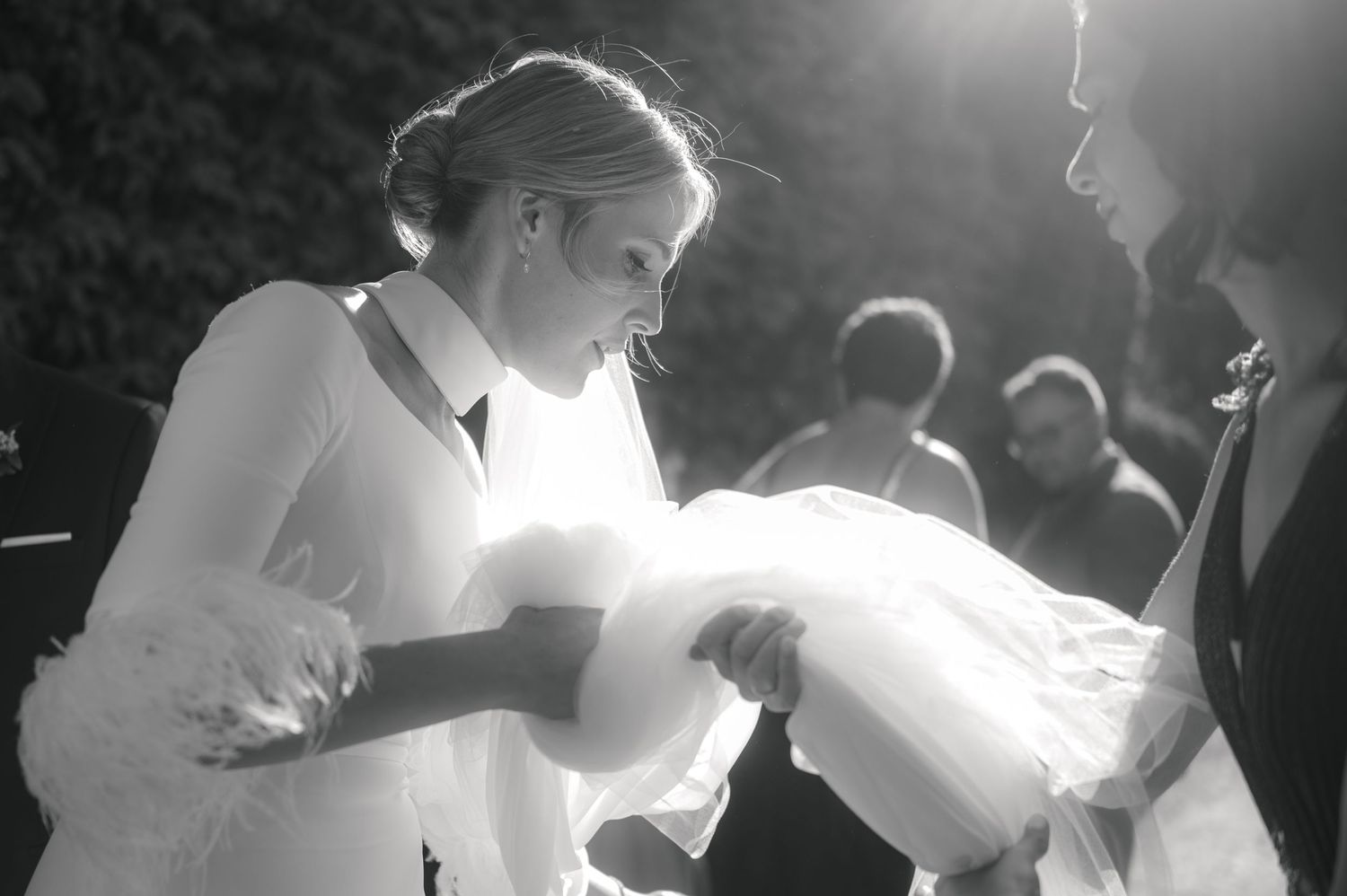 A black and white wedding photo captures a tender moment during an outdoor ceremony.