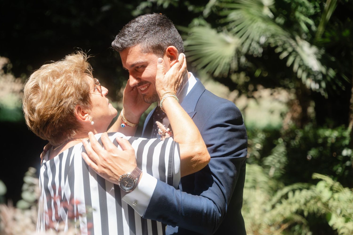 Joyful wedding moment shared between couple and guests in sunlit outdoor setting.
