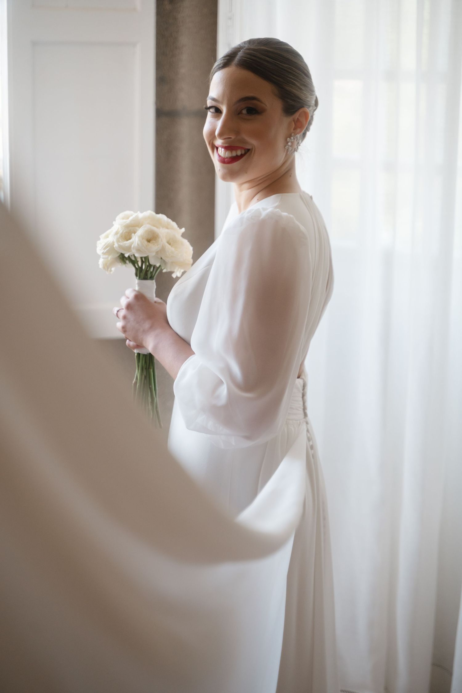 Classic bridal portrait featuring long-sleeved white gown and cream rose bouquet.
