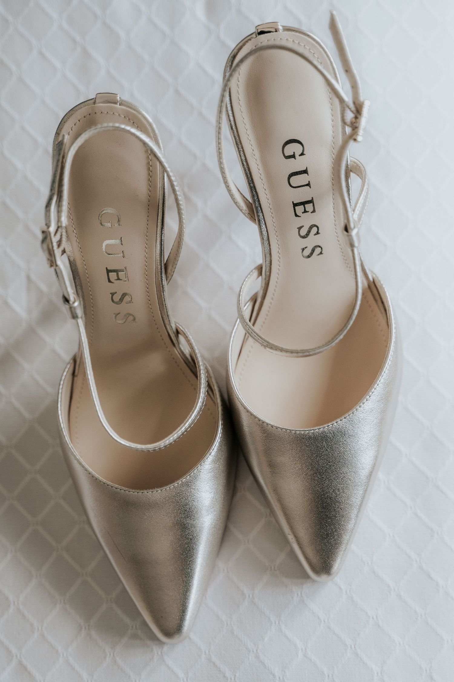 Elegant silver slingback wedding shoes displayed on a textured white background.