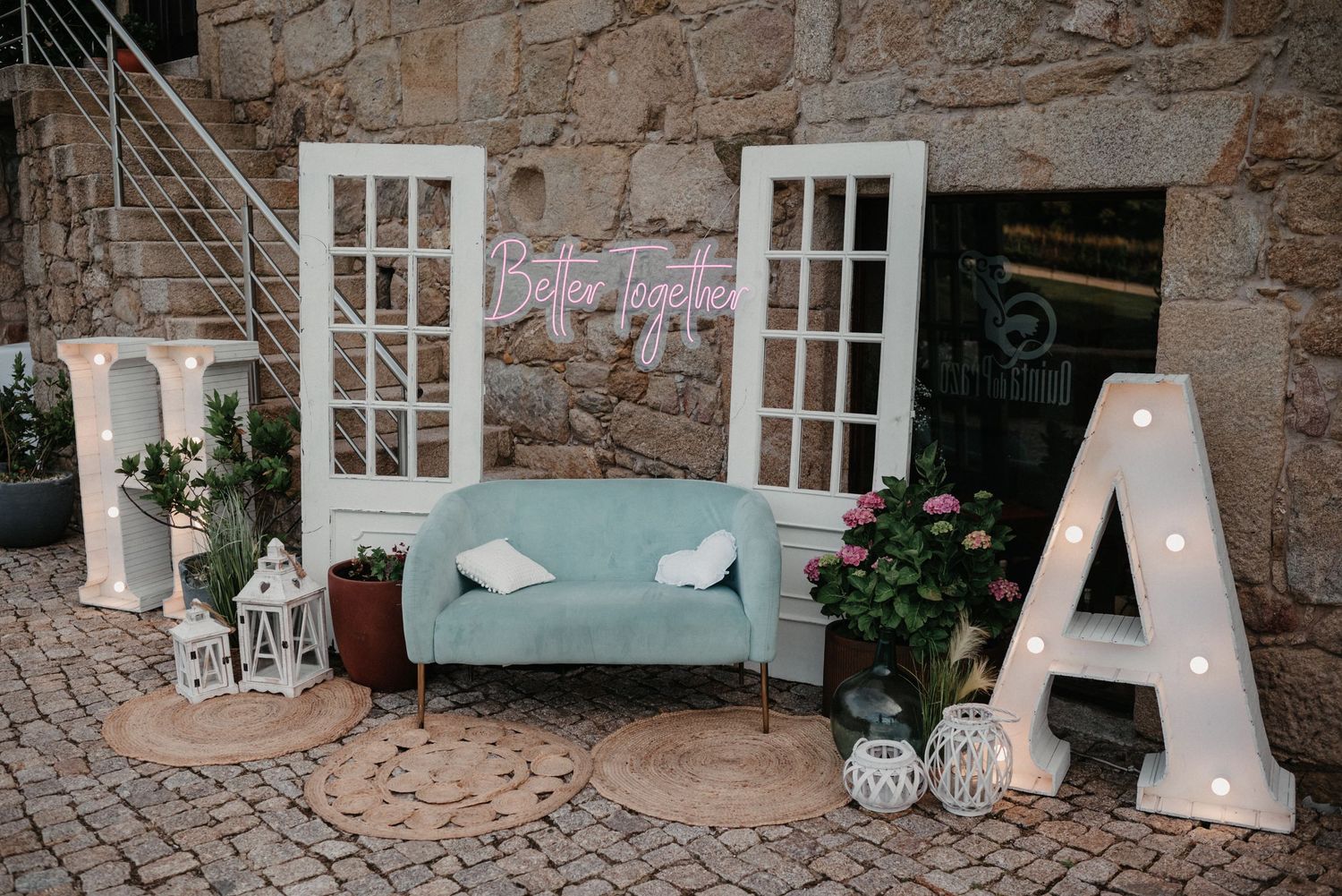 Rustic stone wall venue interior with white-framed windows and romantic lighting setup for an elegant event.
