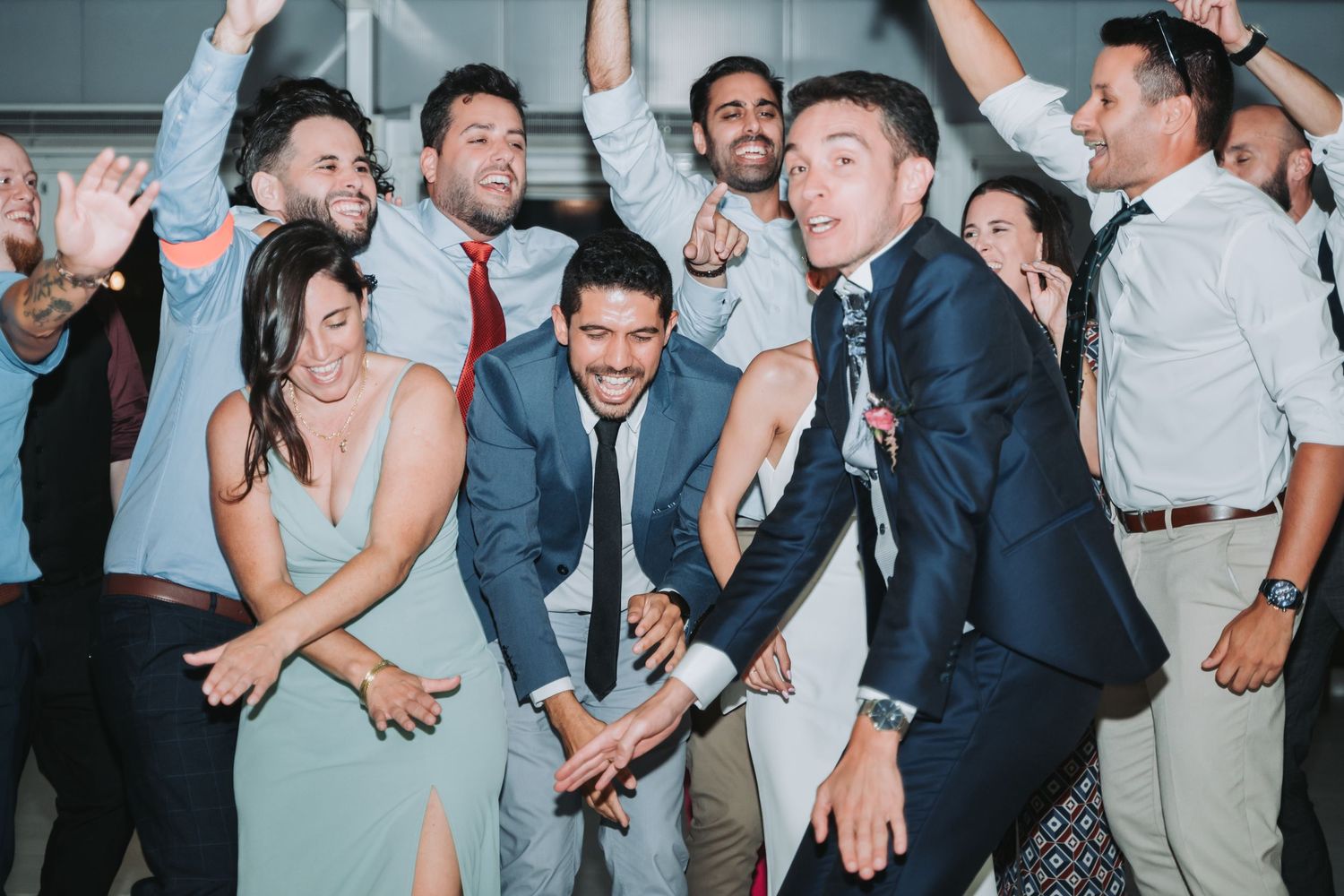Wedding guests dancing and celebrating on a dance floor at a reception party.
