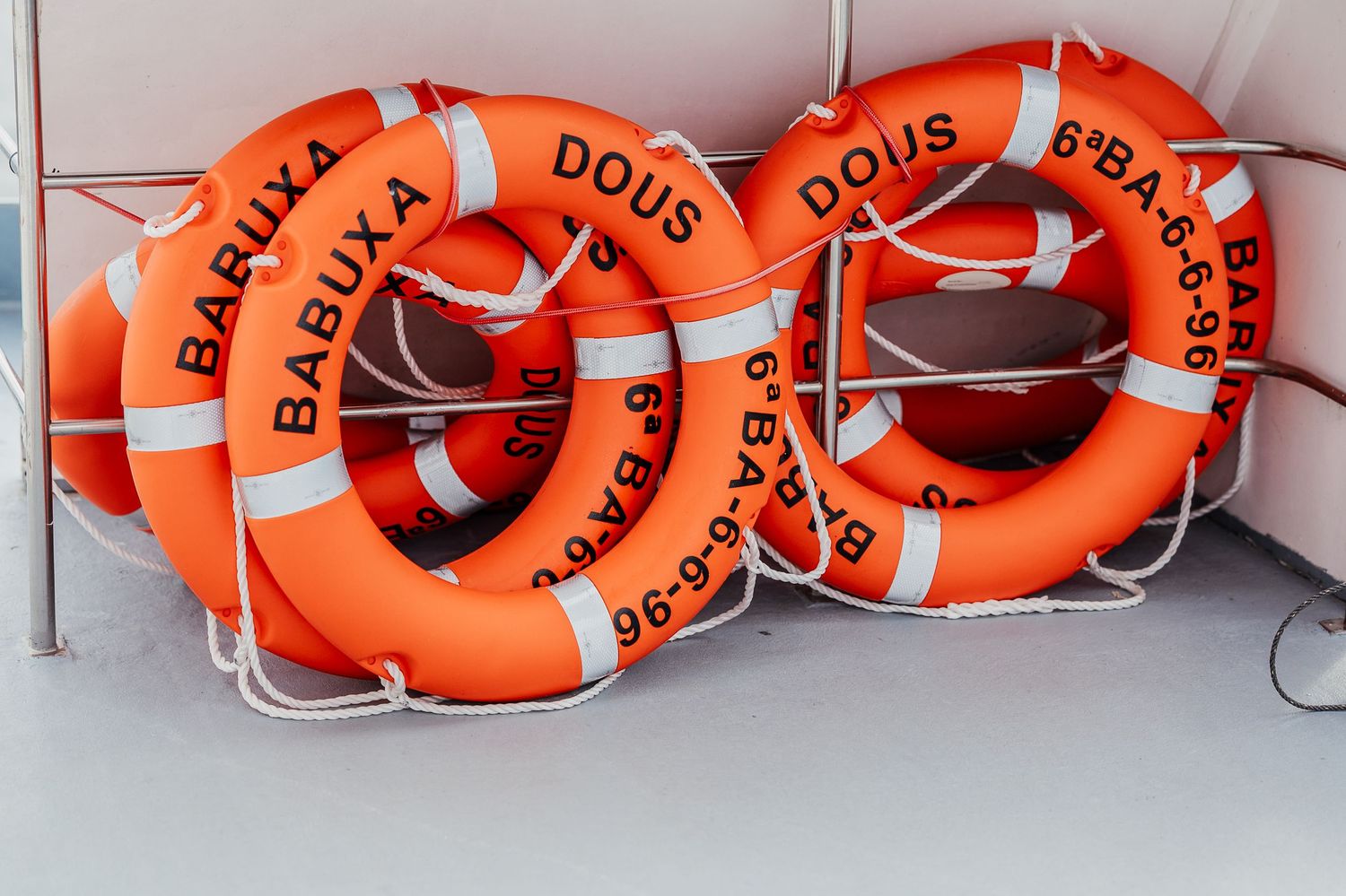 Row of bright orange life preservers with text mounted on a white wall.