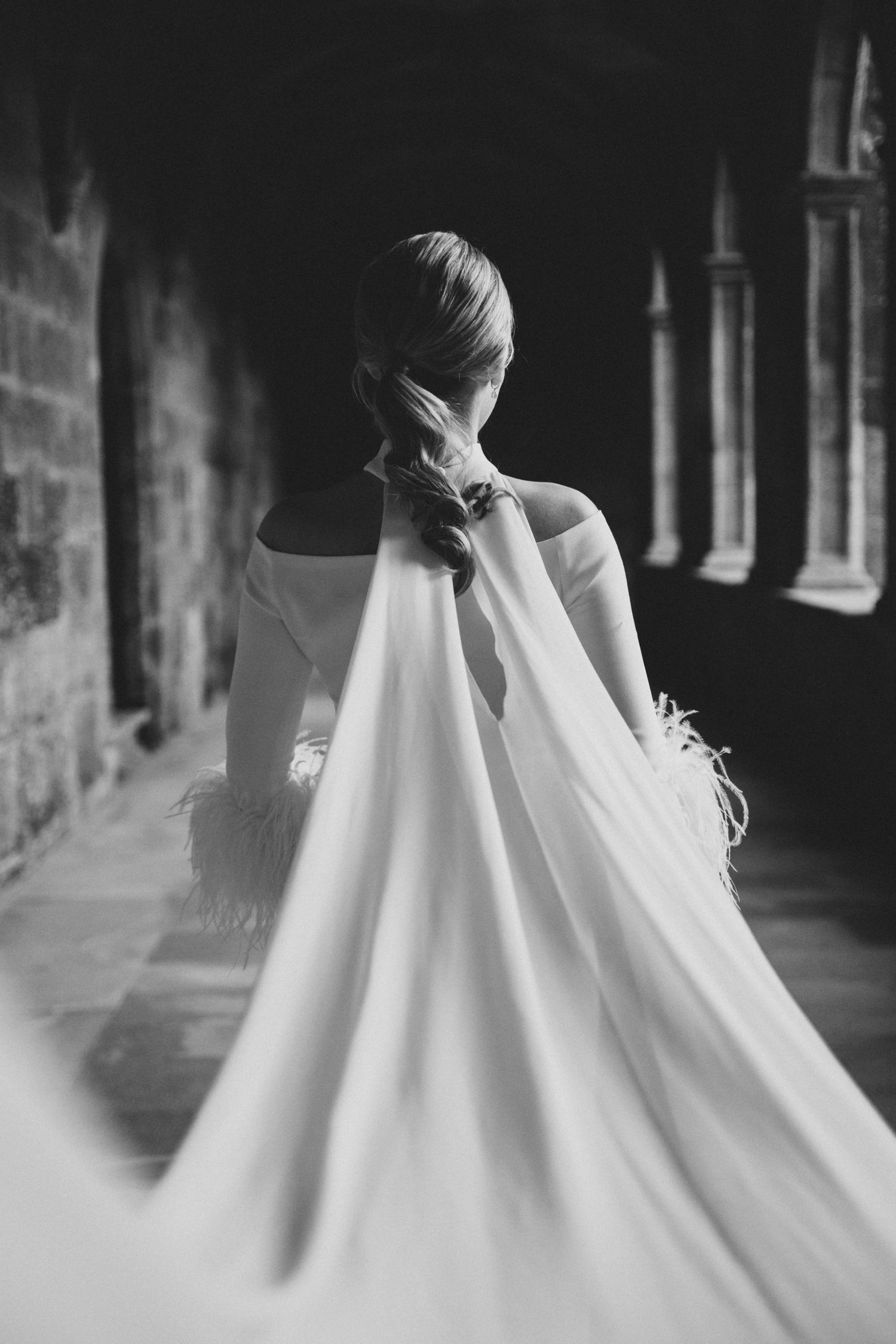 Artistic black and white detail shot of flowing white wedding dress fabric in dramatic lighting.
