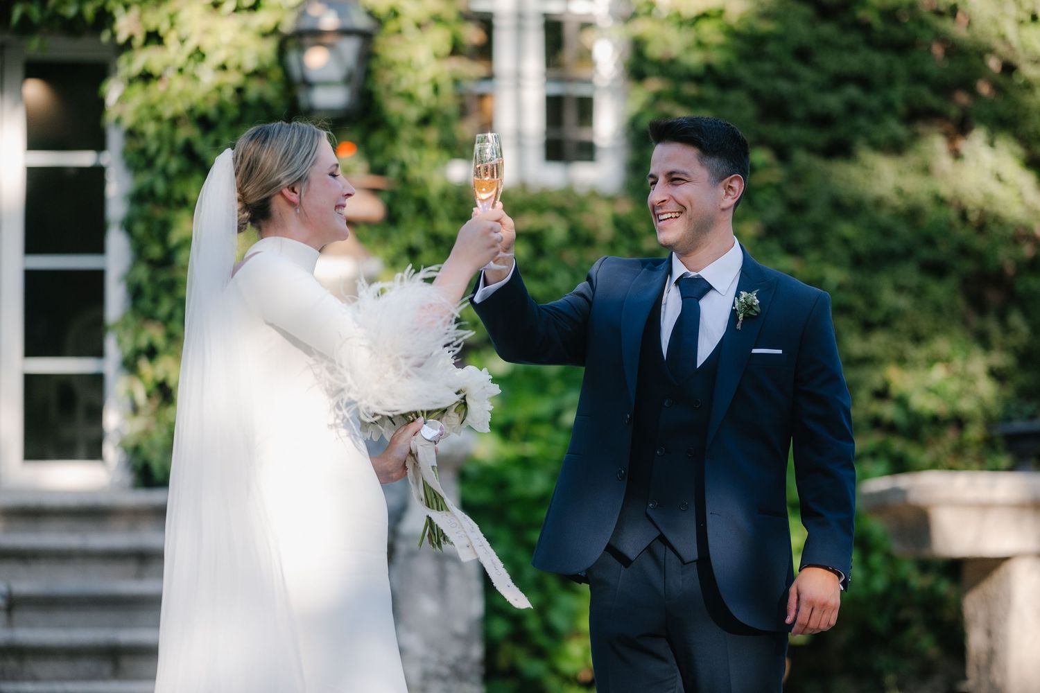 Wedding couple dancing and twirling in a garden setting with greenery in the background.