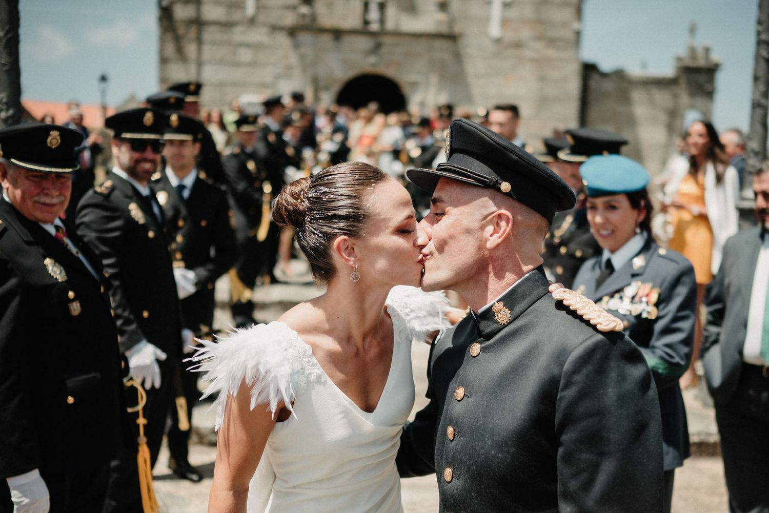 Wedding party celebrates outdoors with stone architecture and military uniforms creating an elegant scene.