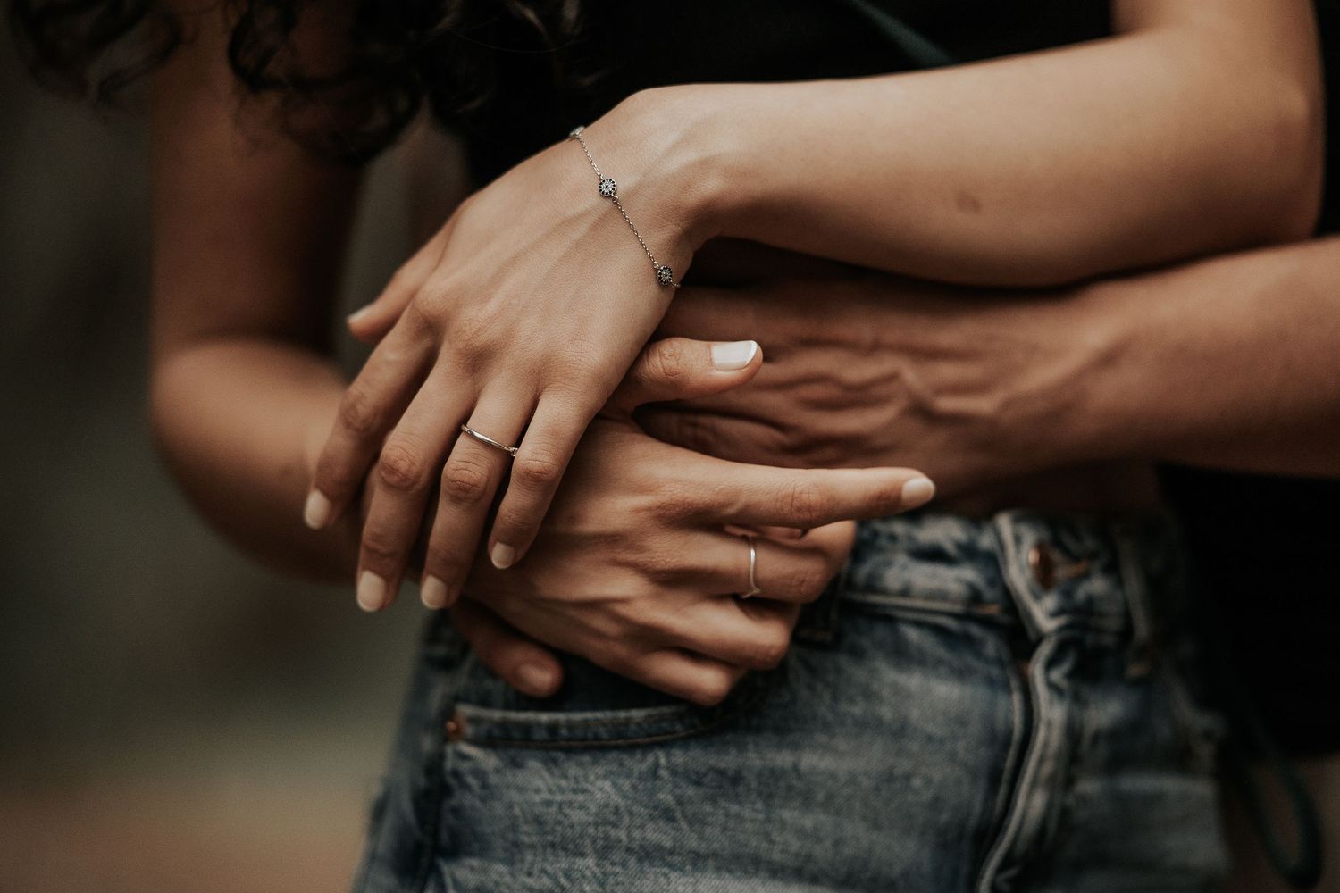 Close-up shot of hands tenderly embracing in a romantic outdoor setting.