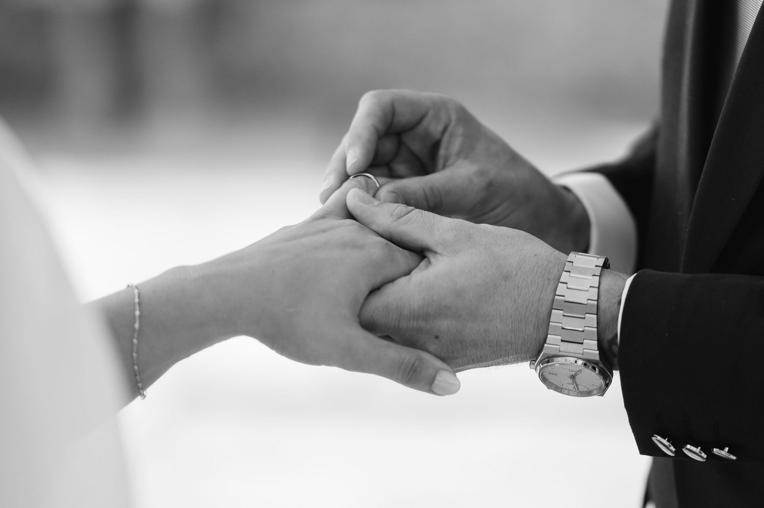 Close-up of hands exchanging small objects in black and white photography.