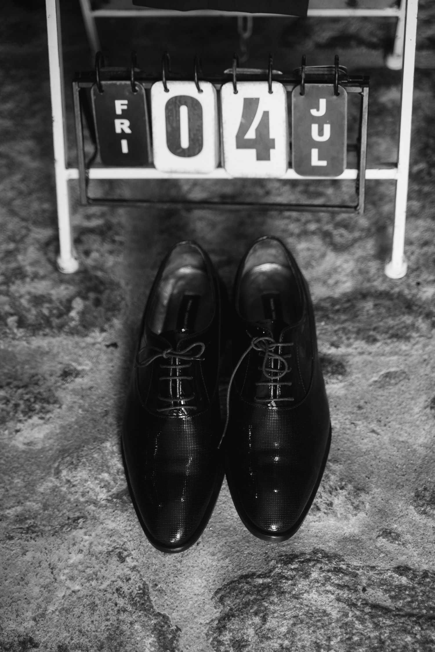 A series of black and white photographs showing polished black dress shoes arranged on a textured surface.