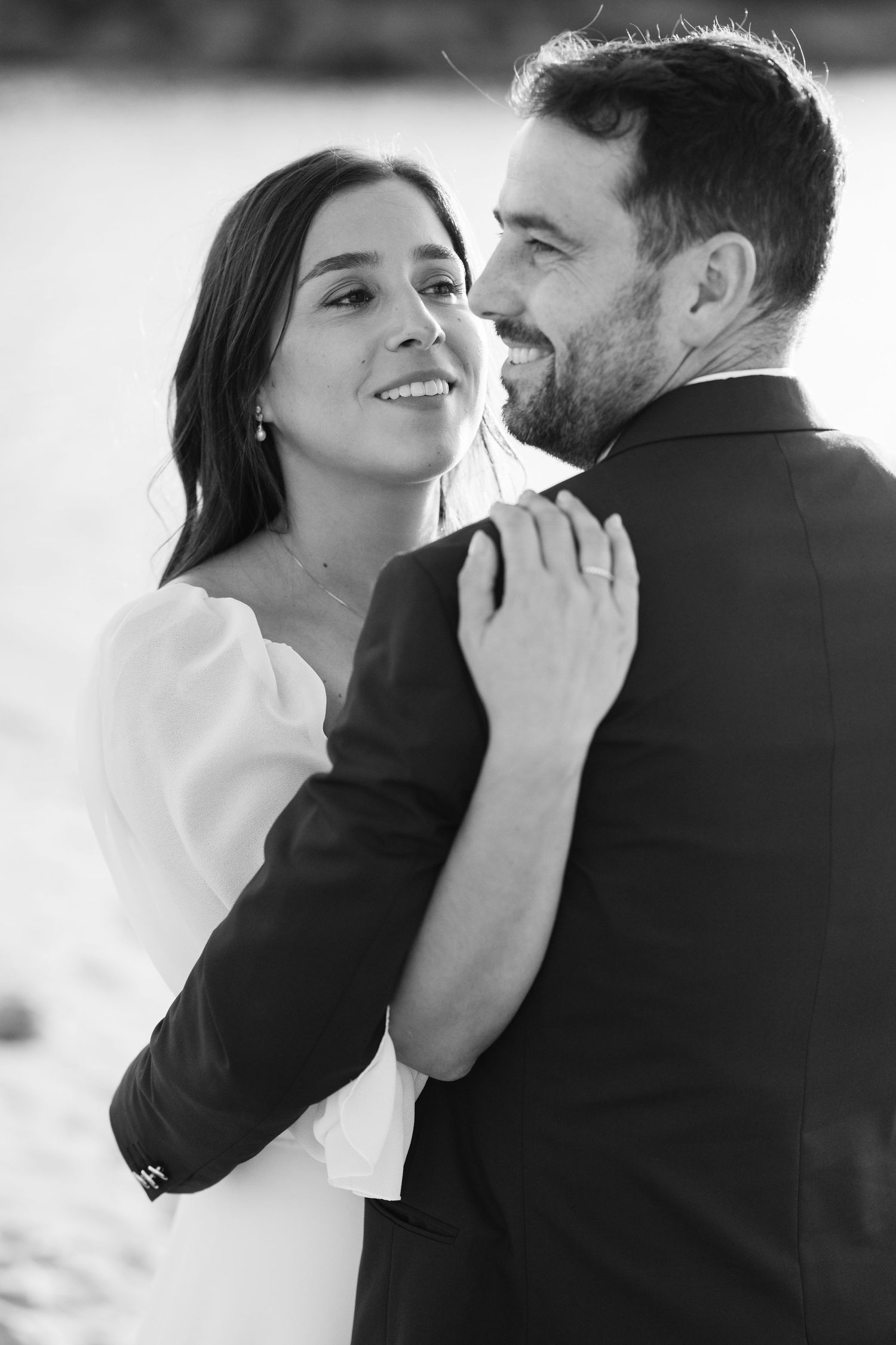 A romantic black and white photo series showing an intimate embrace between a couple in formal wedding attire.