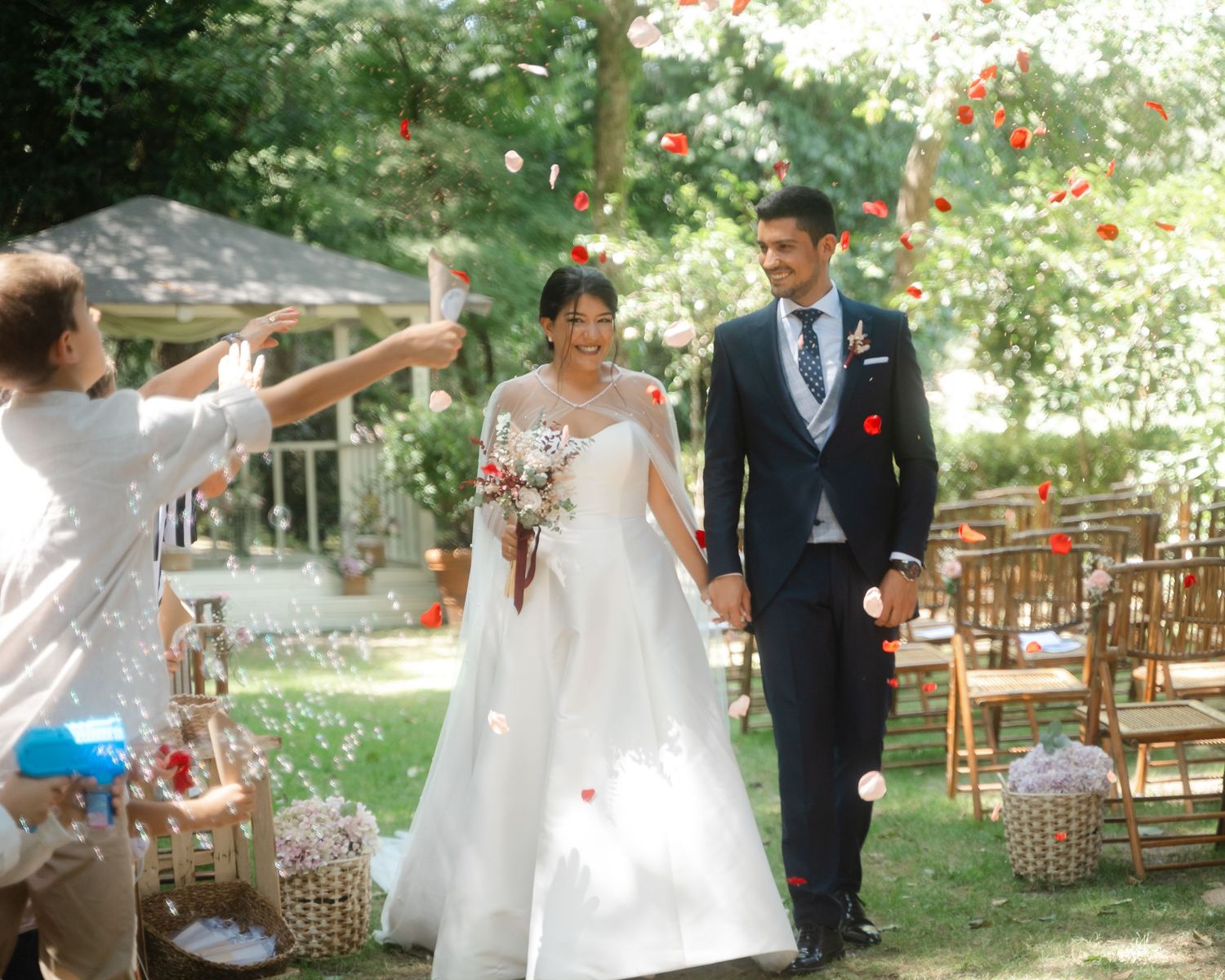 Wedding ceremony setup in an outdoor garden with wooden chairs and natural decor along a path.