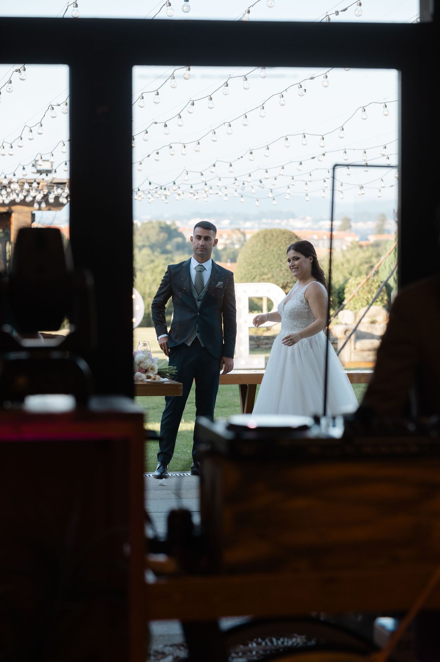 A couple stands in silhouette through a window frame with scenic outdoor views in the background.