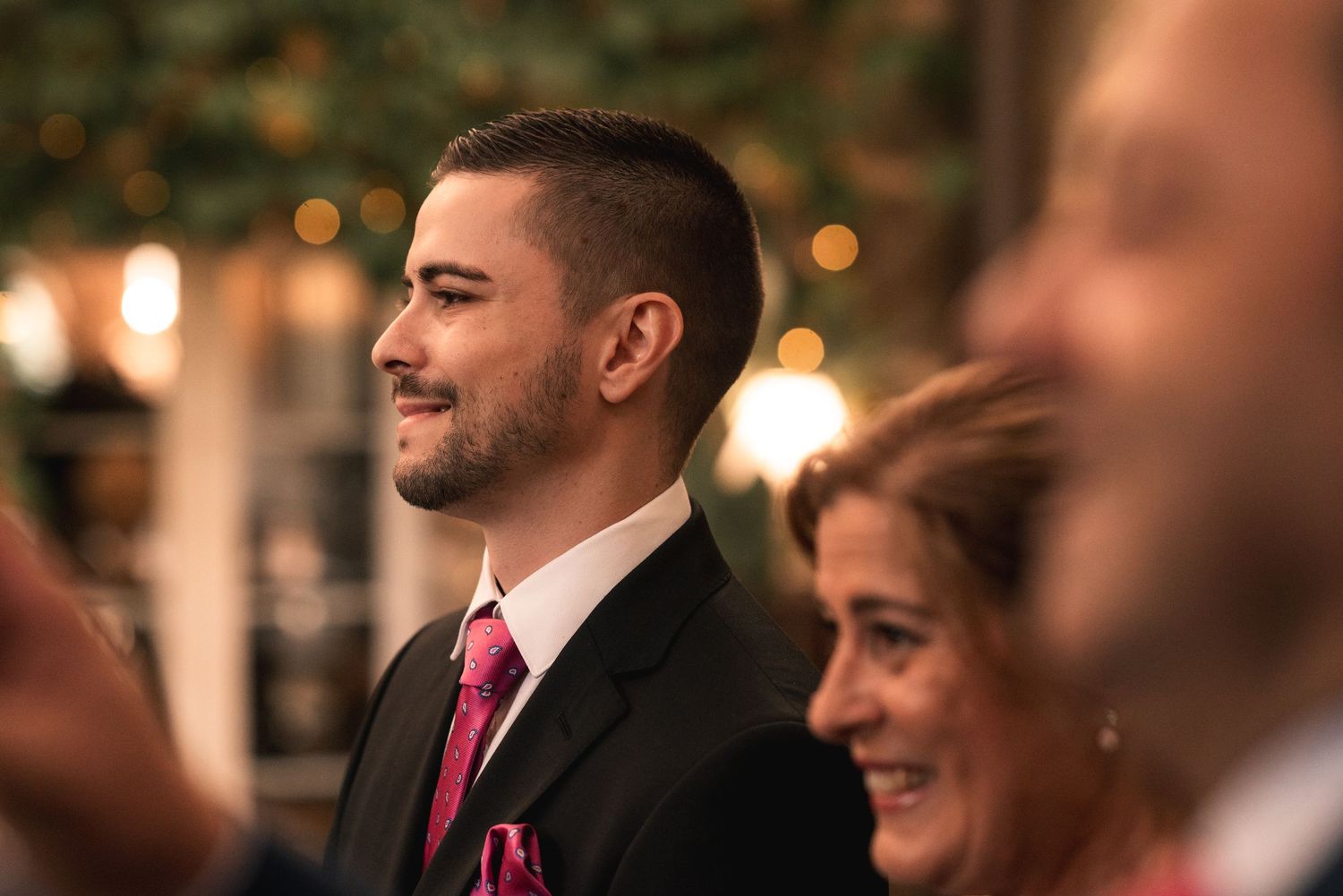 Wedding guests socialize during an evening reception with warm lighting and festive atmosphere.