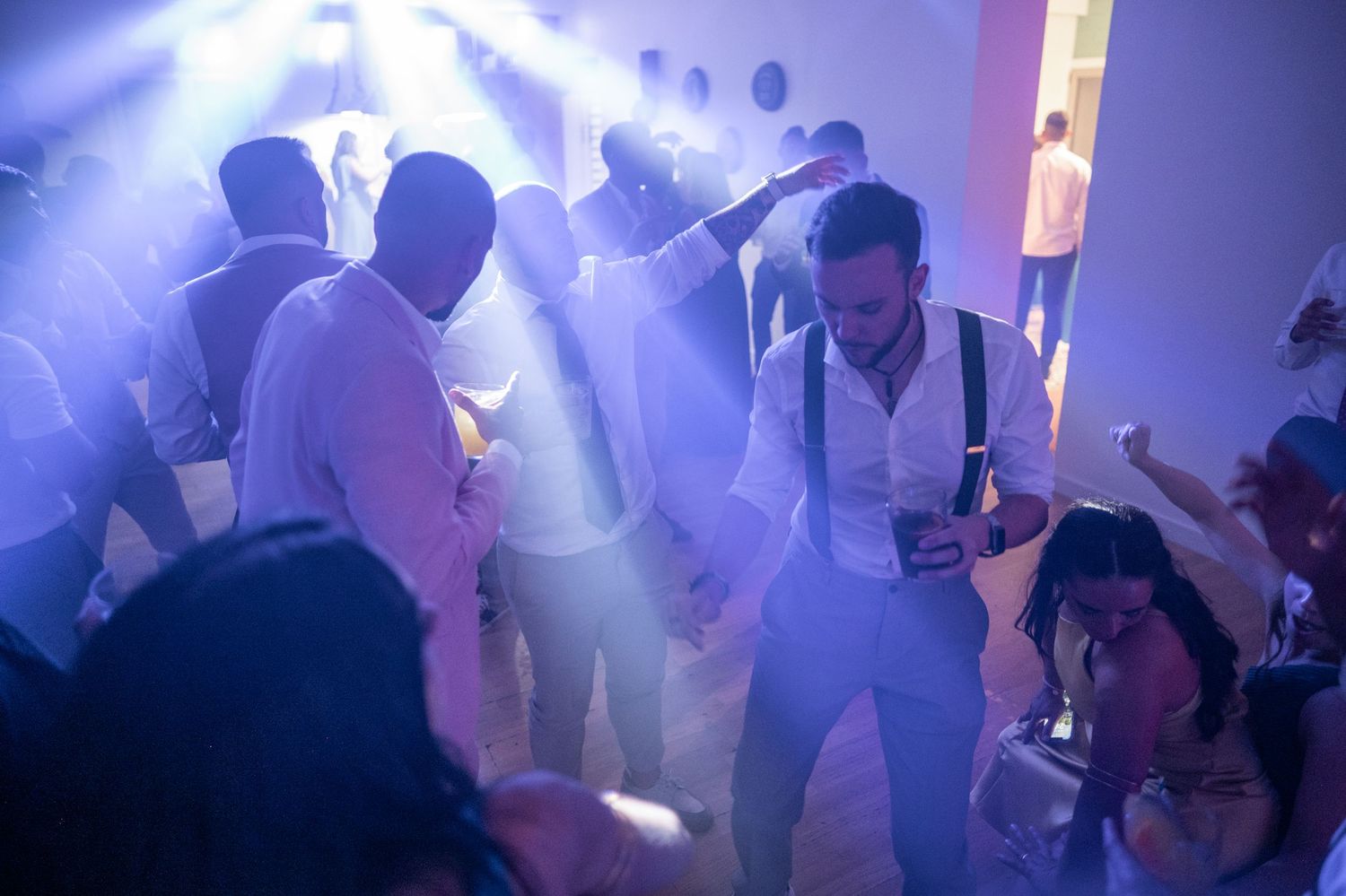 Crowd dancing under blue lighting effects at a nightclub or party venue.