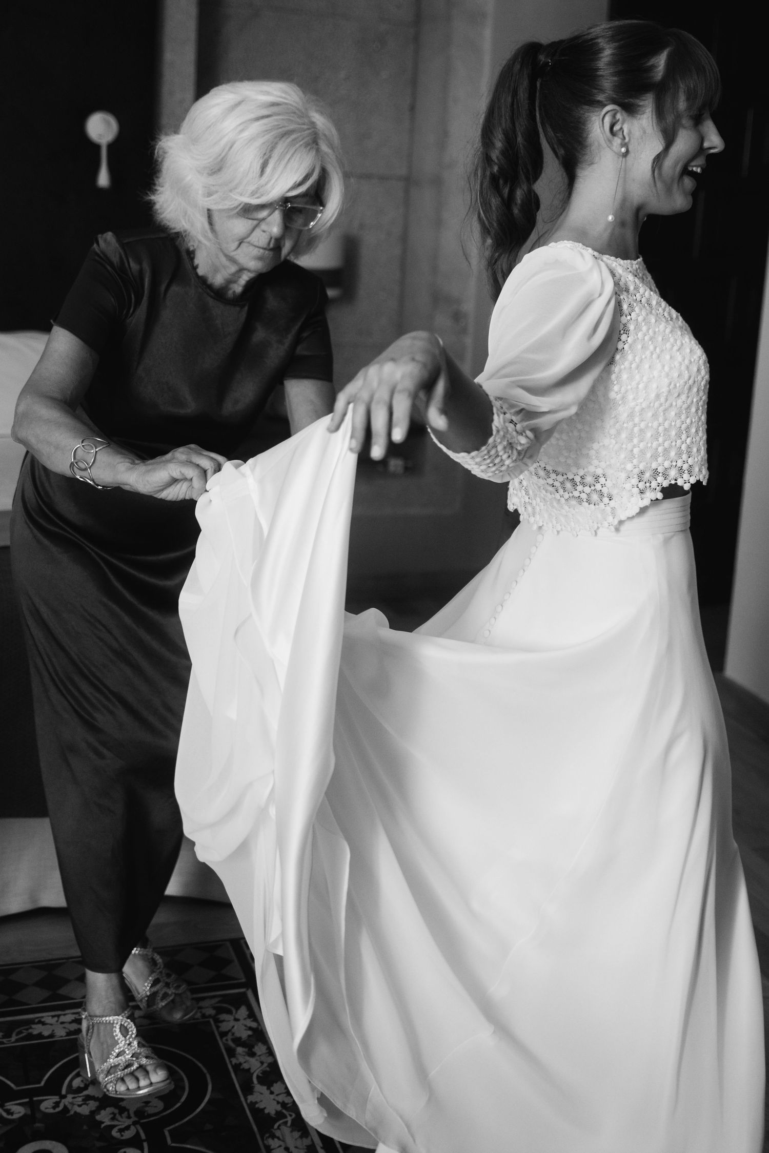 A series of black and white photos capturing the process of putting on a wedding dress with assistance.