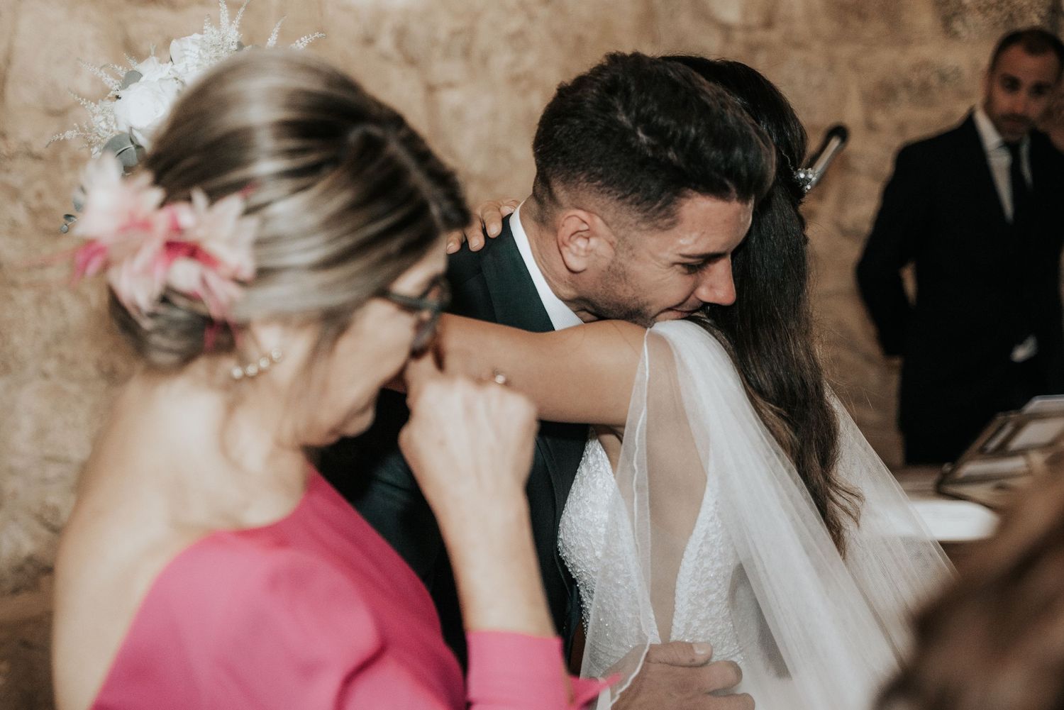 Wedding party members share emotional moments and embraces during an intimate celebration.