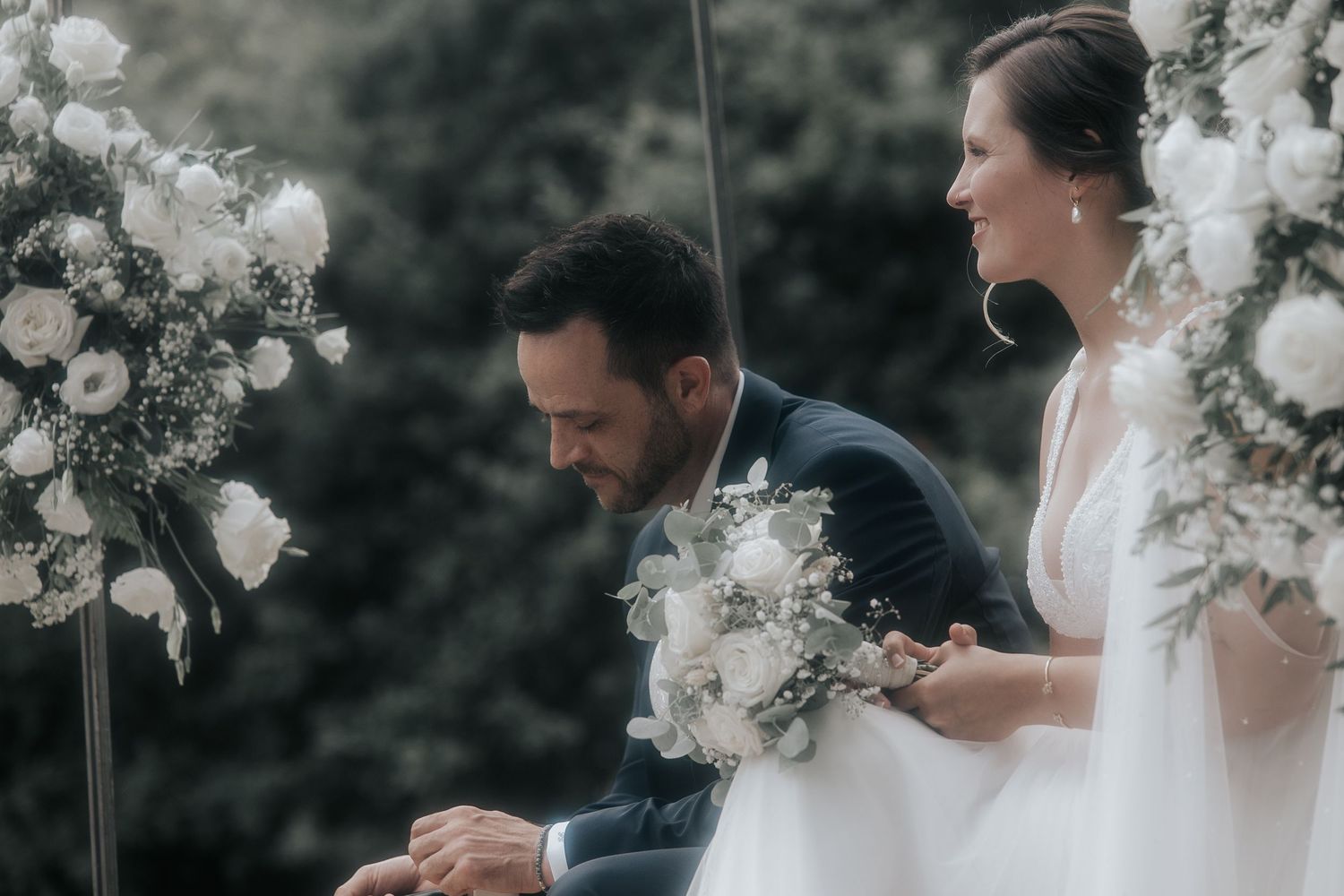 Emotional wedding scene with floral arrangements and white decor as a couple embraces during their ceremony.
