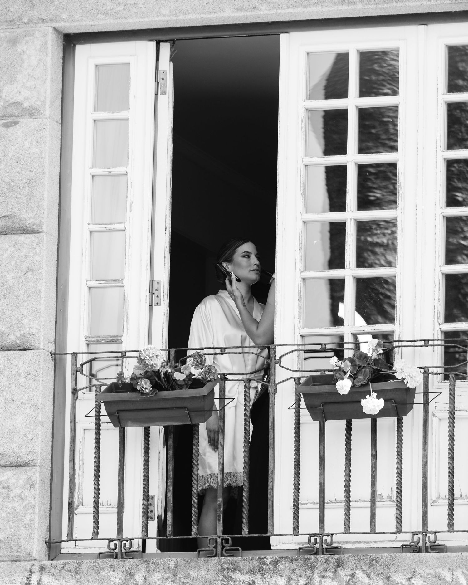 Black and white photograph showing people standing at multiple balconies of a stone building with French doors.