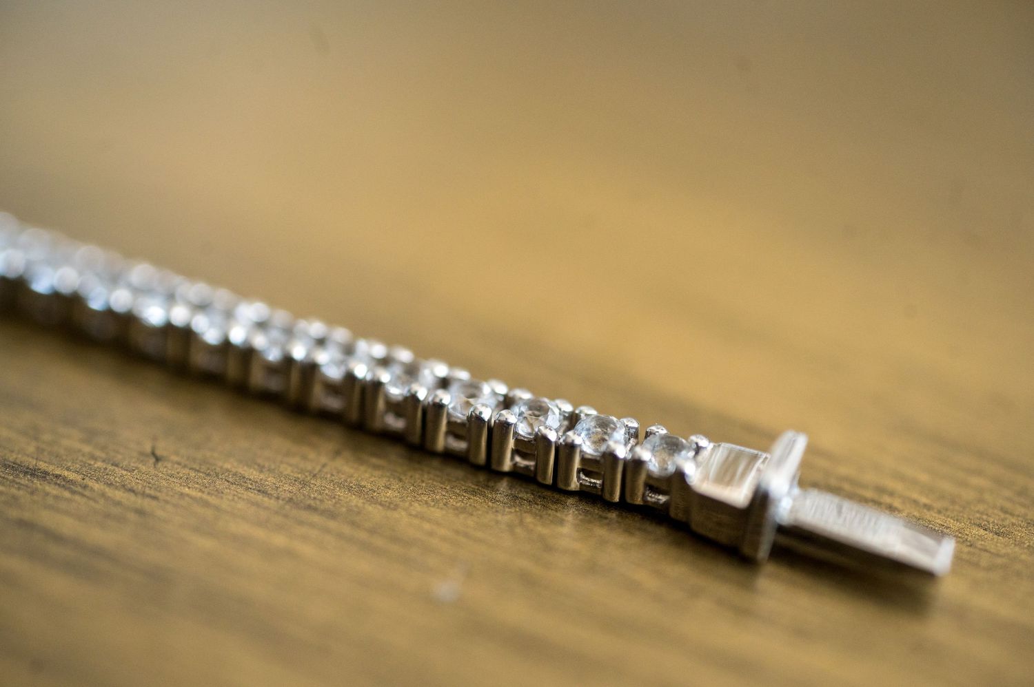 Close-up macro shot of metal screws lined up in a row on a wooden surface.