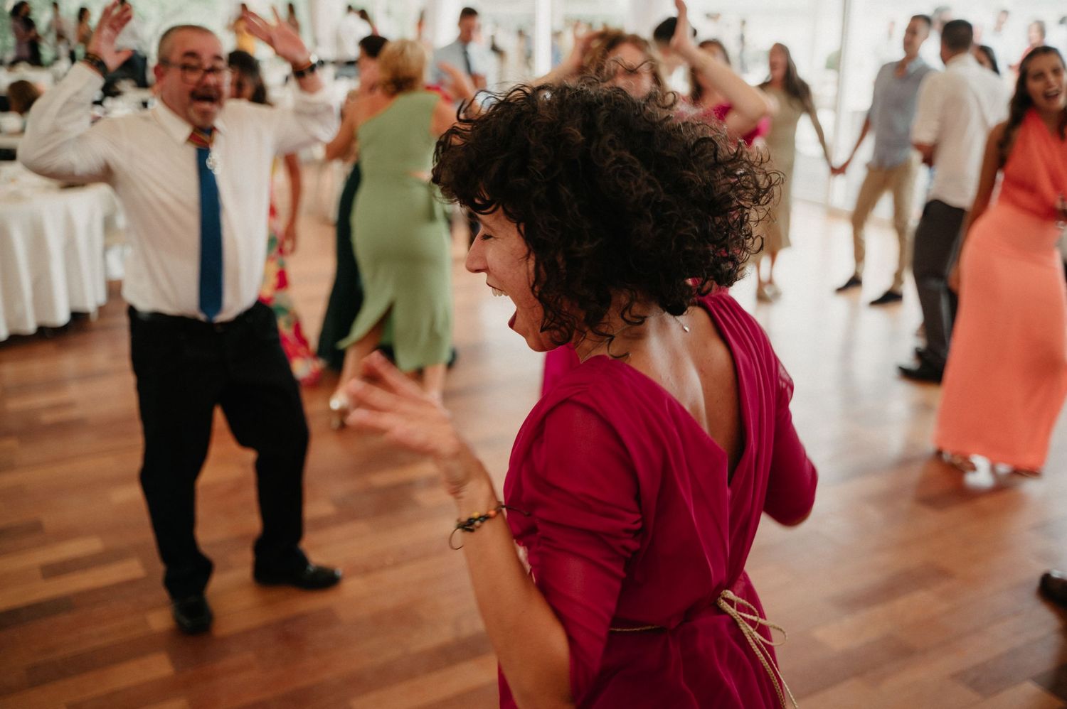 People dancing together in a ballroom with hardwood floors and white walls during a social dance event.