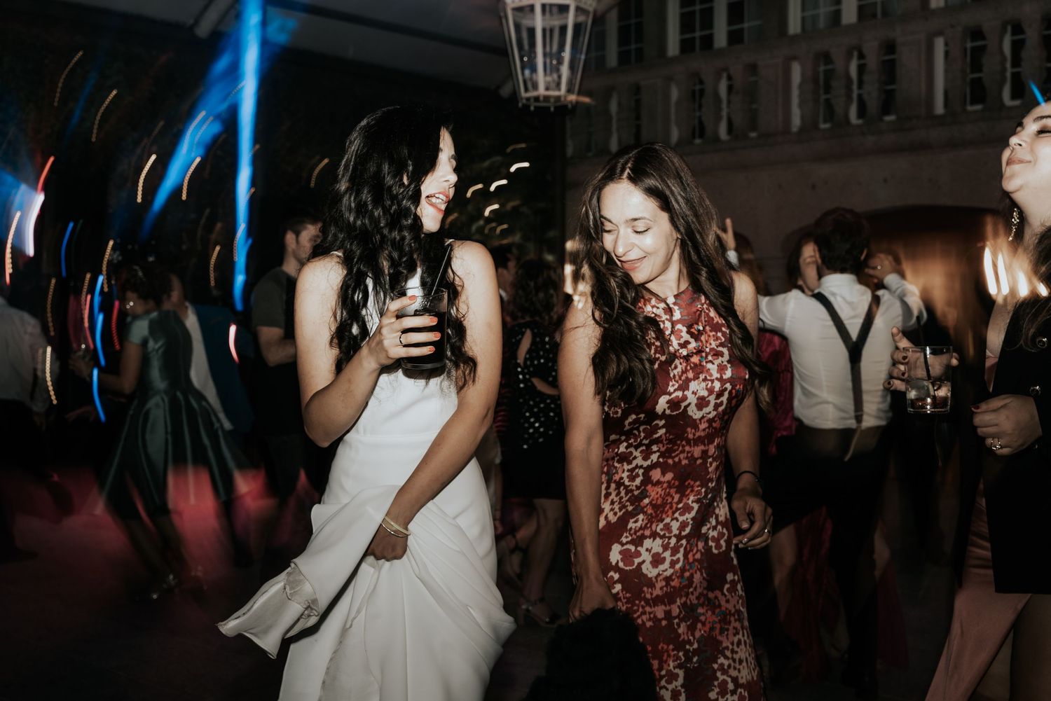 People dancing under blue lighting at a nighttime party or celebration event.