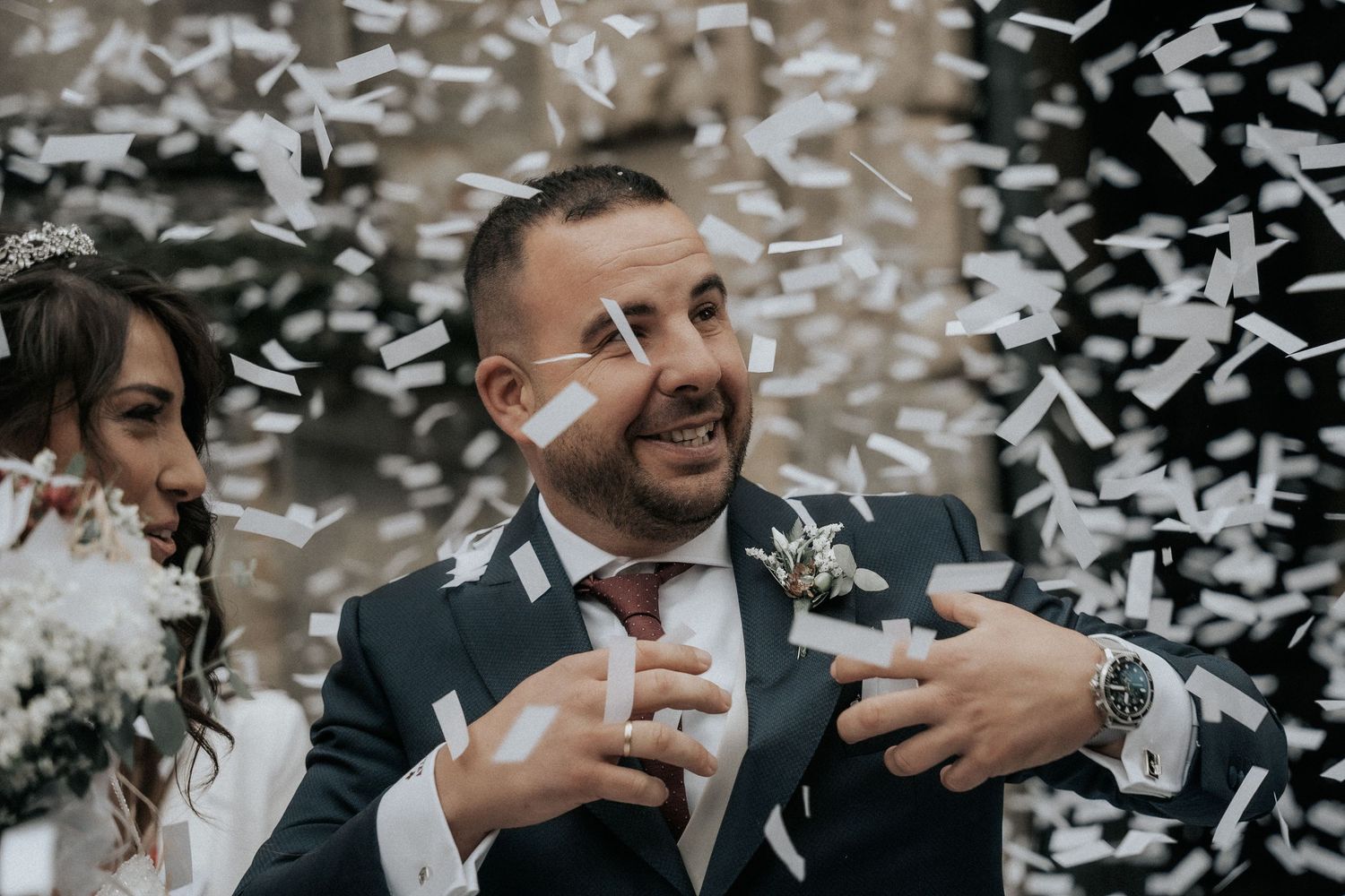 Confetti fills the air during an outdoor wedding celebration with happy reactions.