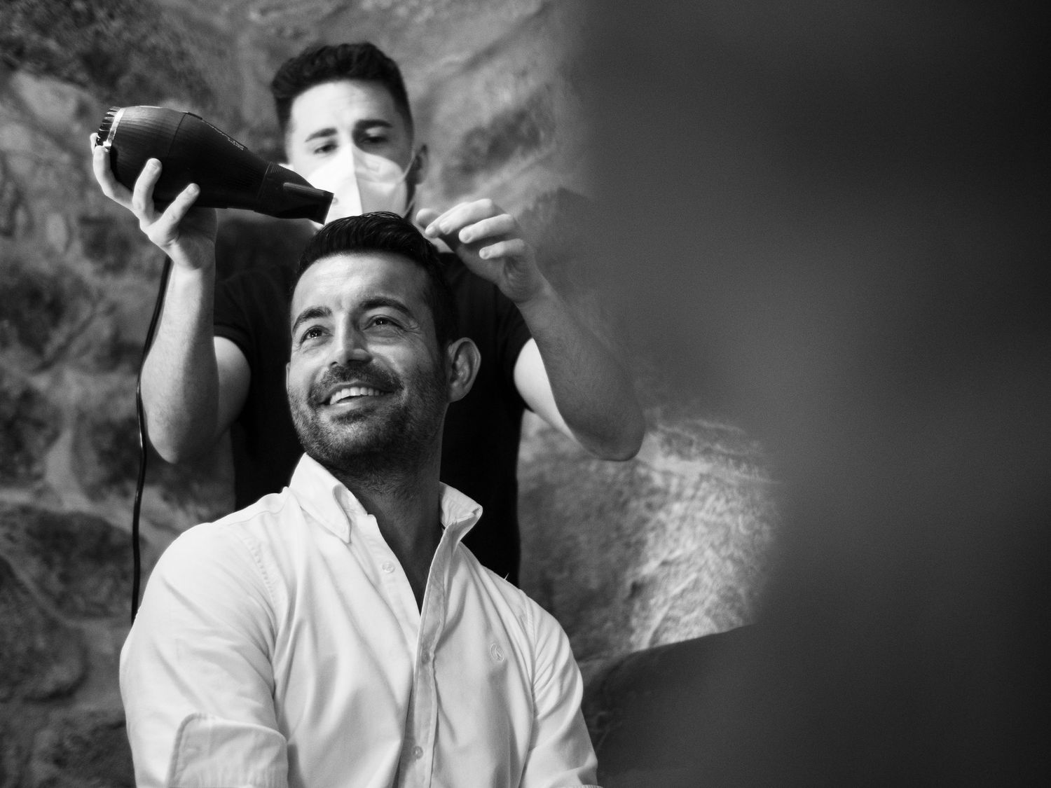 Black and white portrait series showing candid emotional expressions against a stone wall background.
