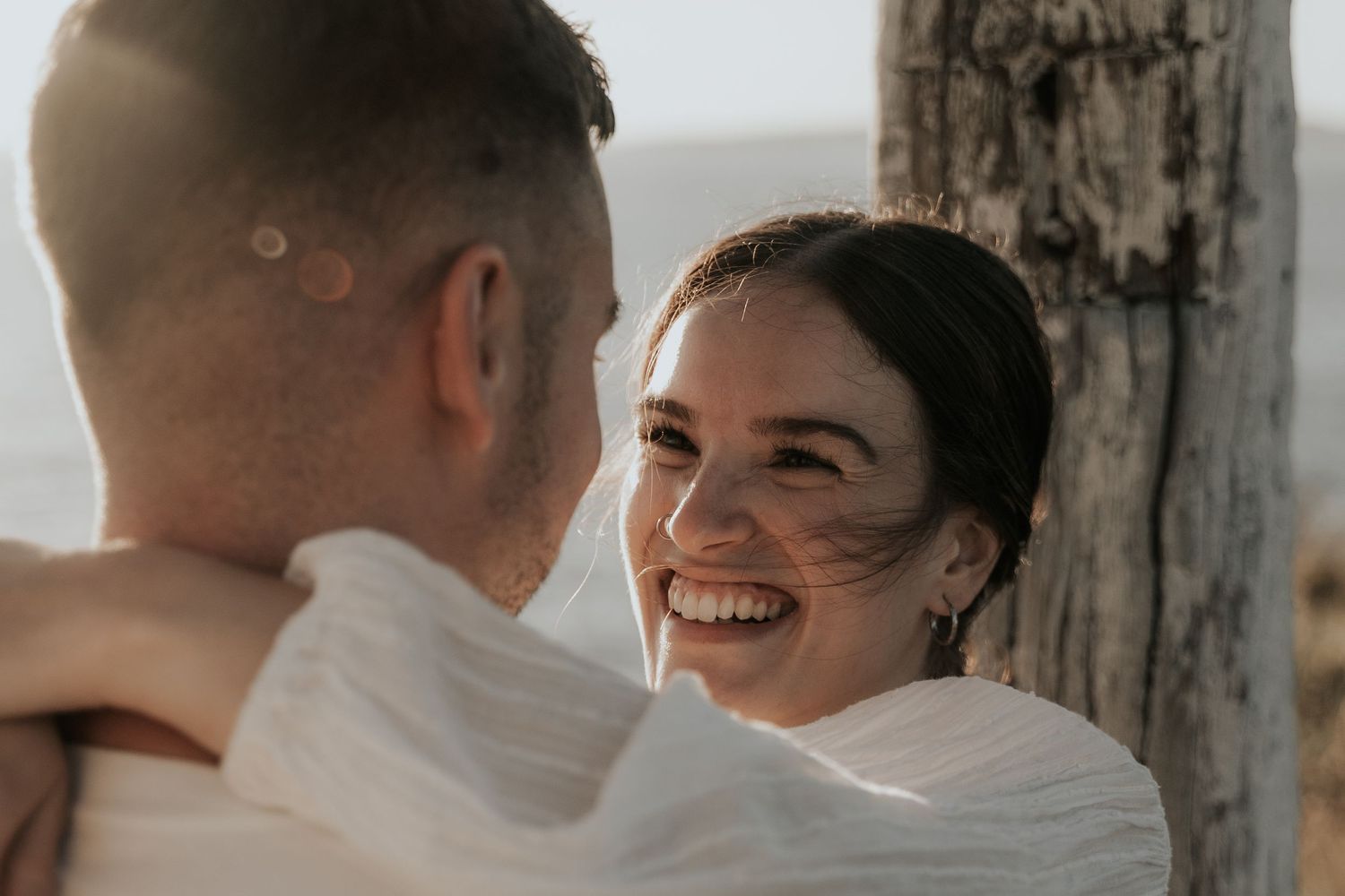 Couple sharing intimate moment outdoors against rustic wooden backdrop.