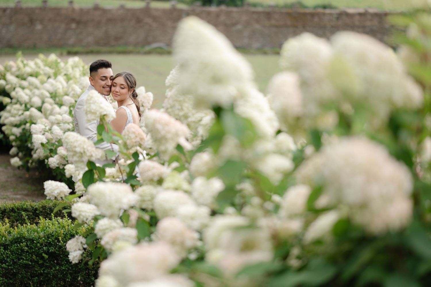 A romantic moment captured in a lush garden with blooming white hydrangeas creating a dreamy atmosphere.