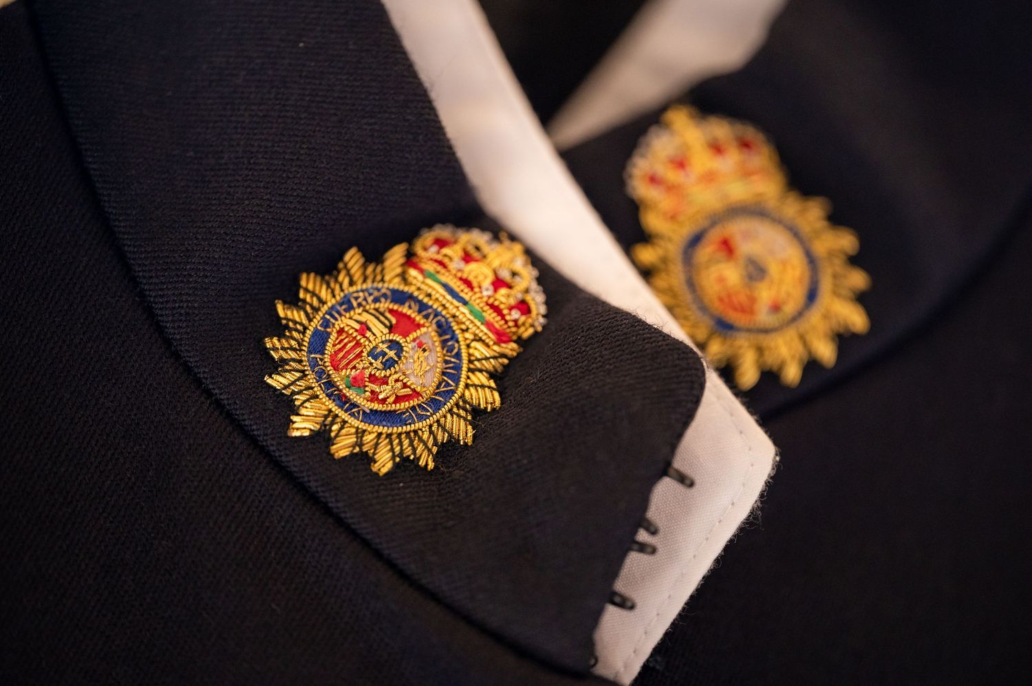 A sequence of close-up shots showing a Salvation Army pin being placed on a dark fabric surface.