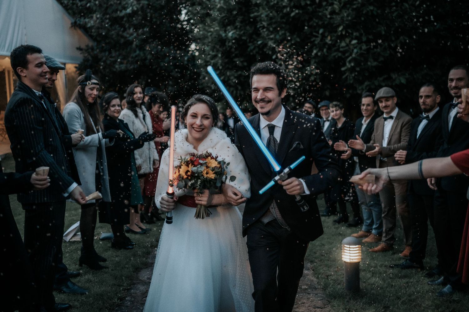 Wedding guests form a pathway holding sparklers as the couple celebrates their special day.